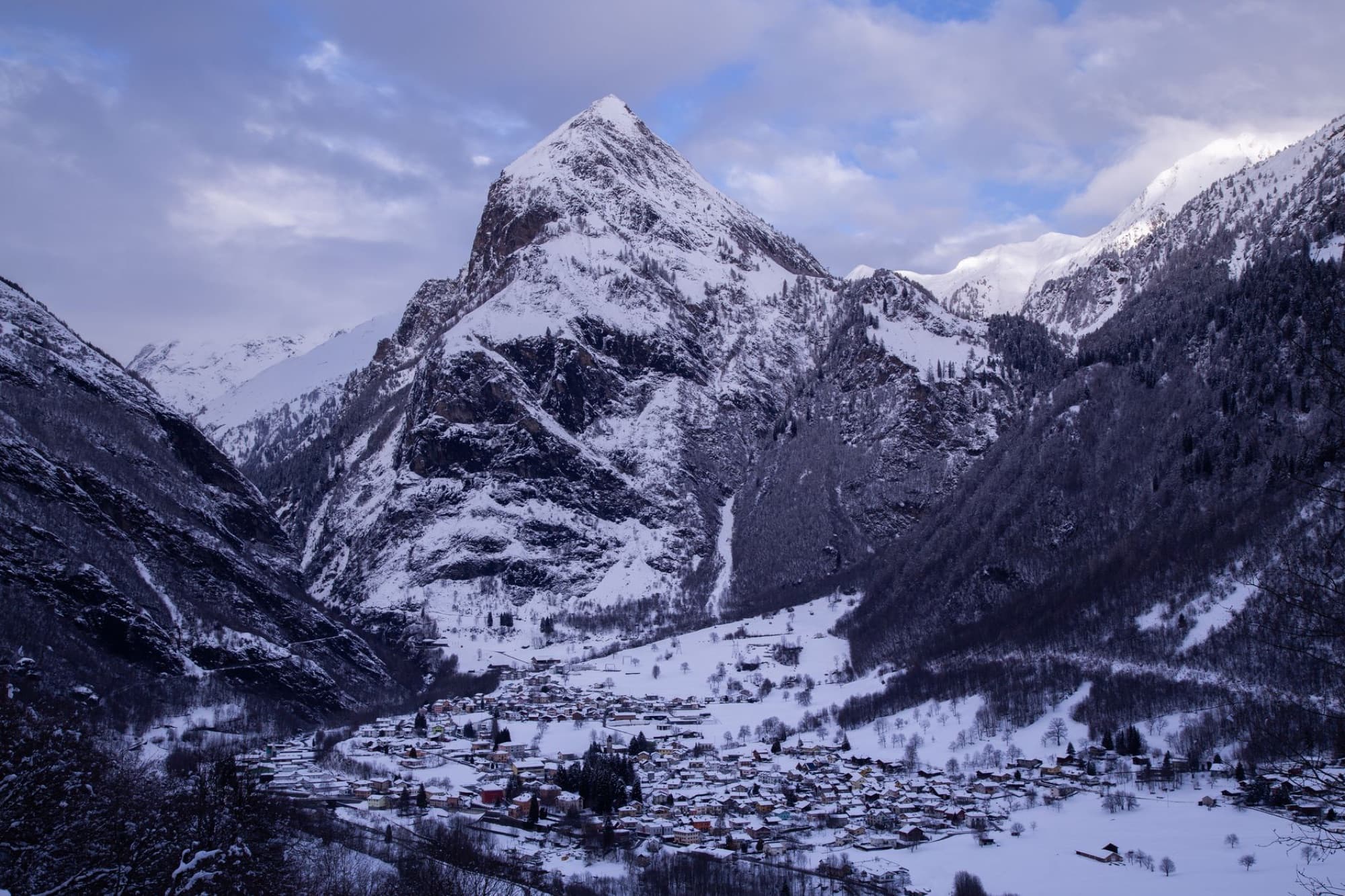 Scenic aerial view of a snow-covered village nestled in winter mountains with dramatic landscape.