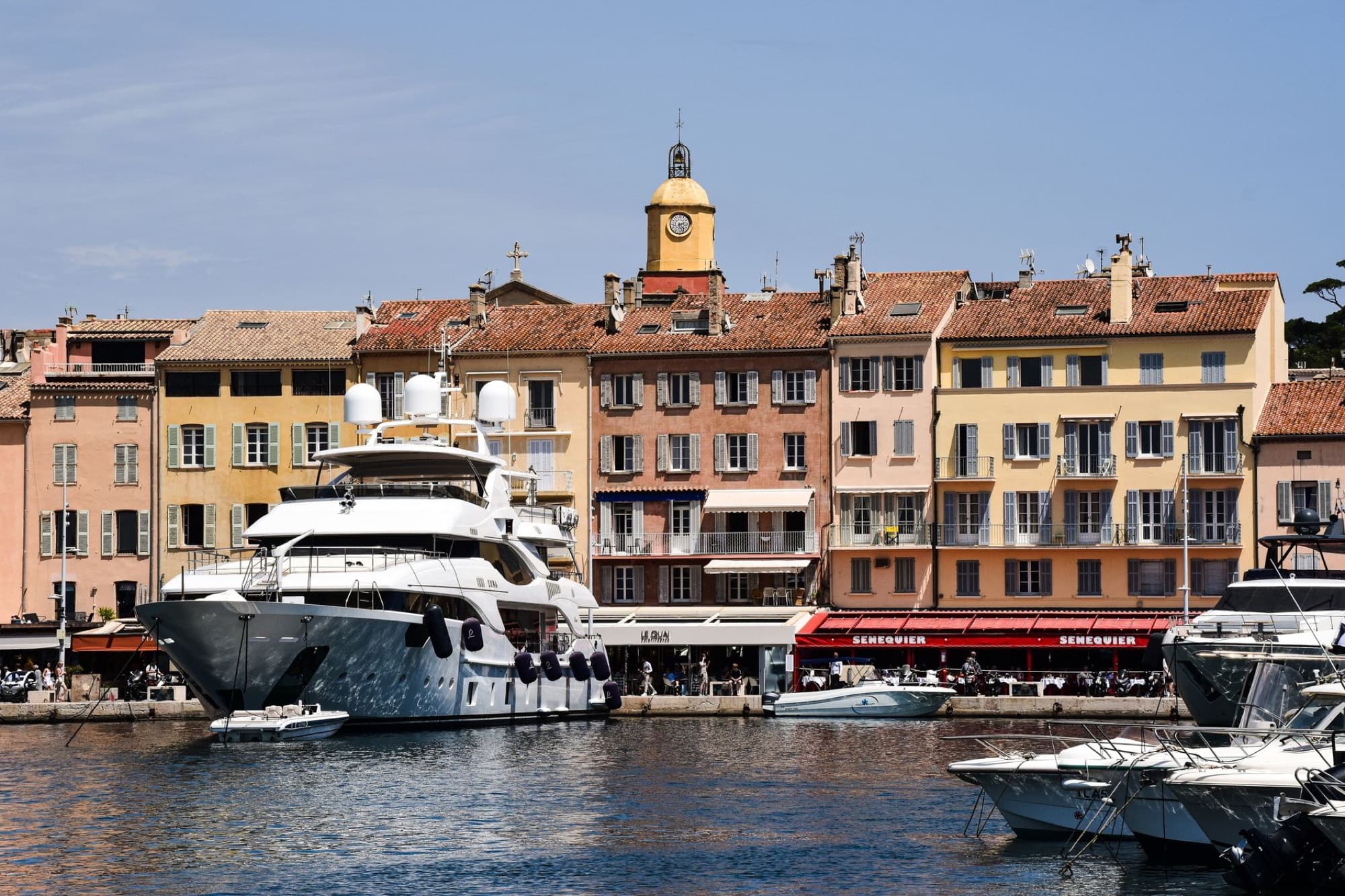 Scenic view of luxury yachts docked at Saint-Tropez harbor with charming French architecture.