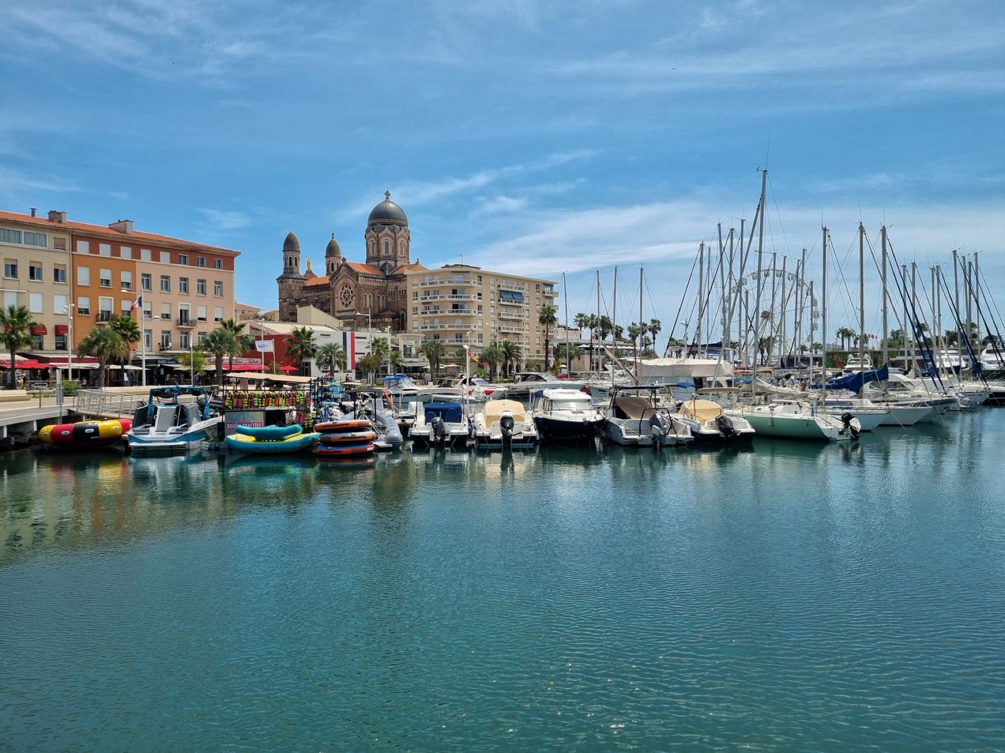 Scenic view of Saint-Tropez marina with boats and the iconic cathedral on a sunny day.