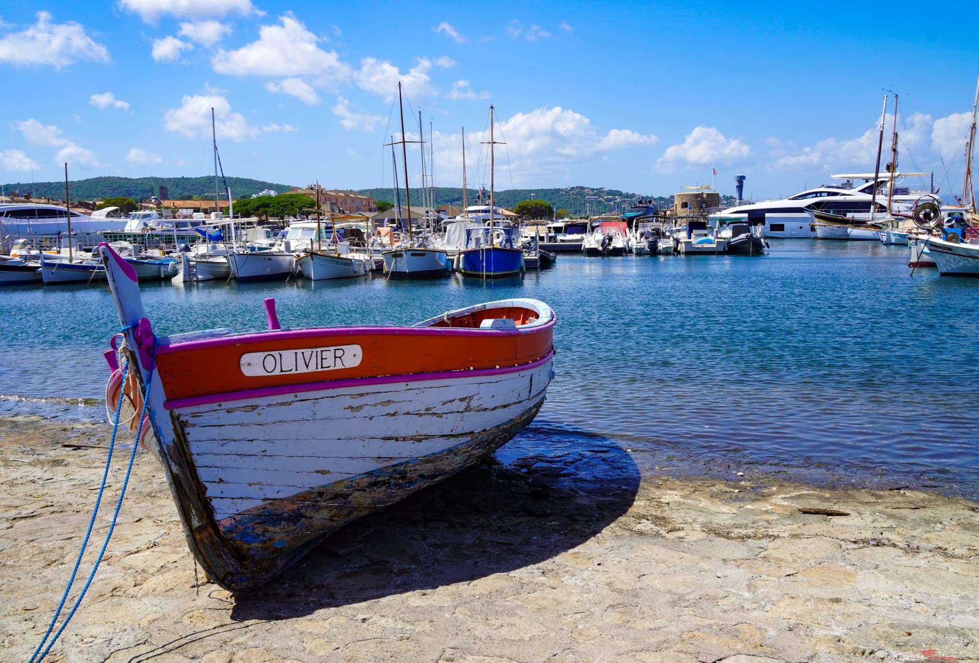 A vibrant scene of traditional wooden boats docked in the charming harbor of Saint-Tropez under a clear blue sky.