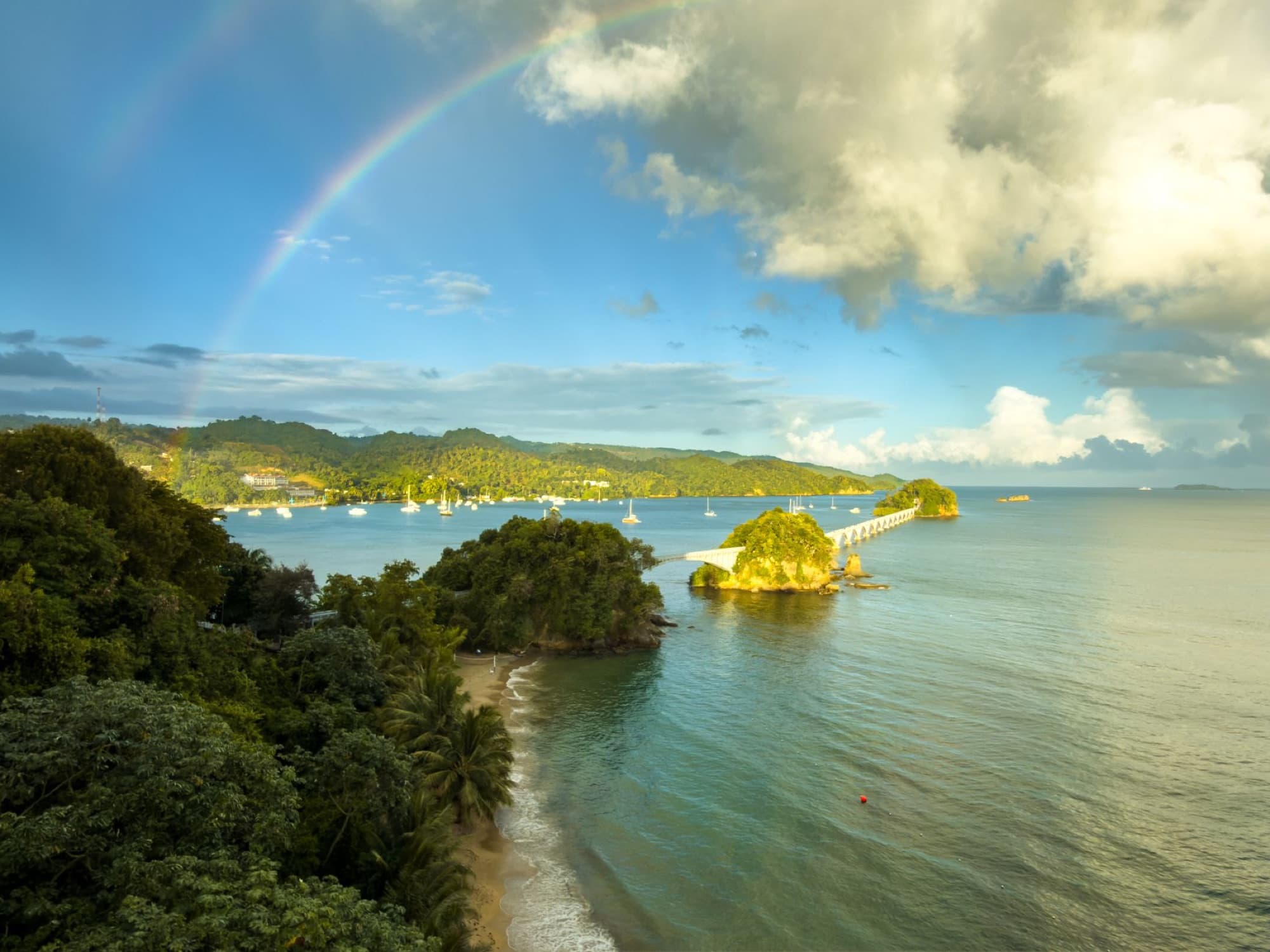 Captivating view of a rainbow arching over lush Samana Bay and coral sand beaches in the Dominican Republic.