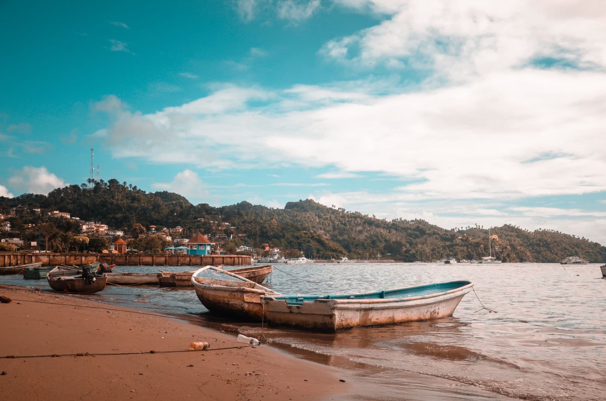 Serene beach with boats in Samaná, Dominican Republic under a vibrant sky.