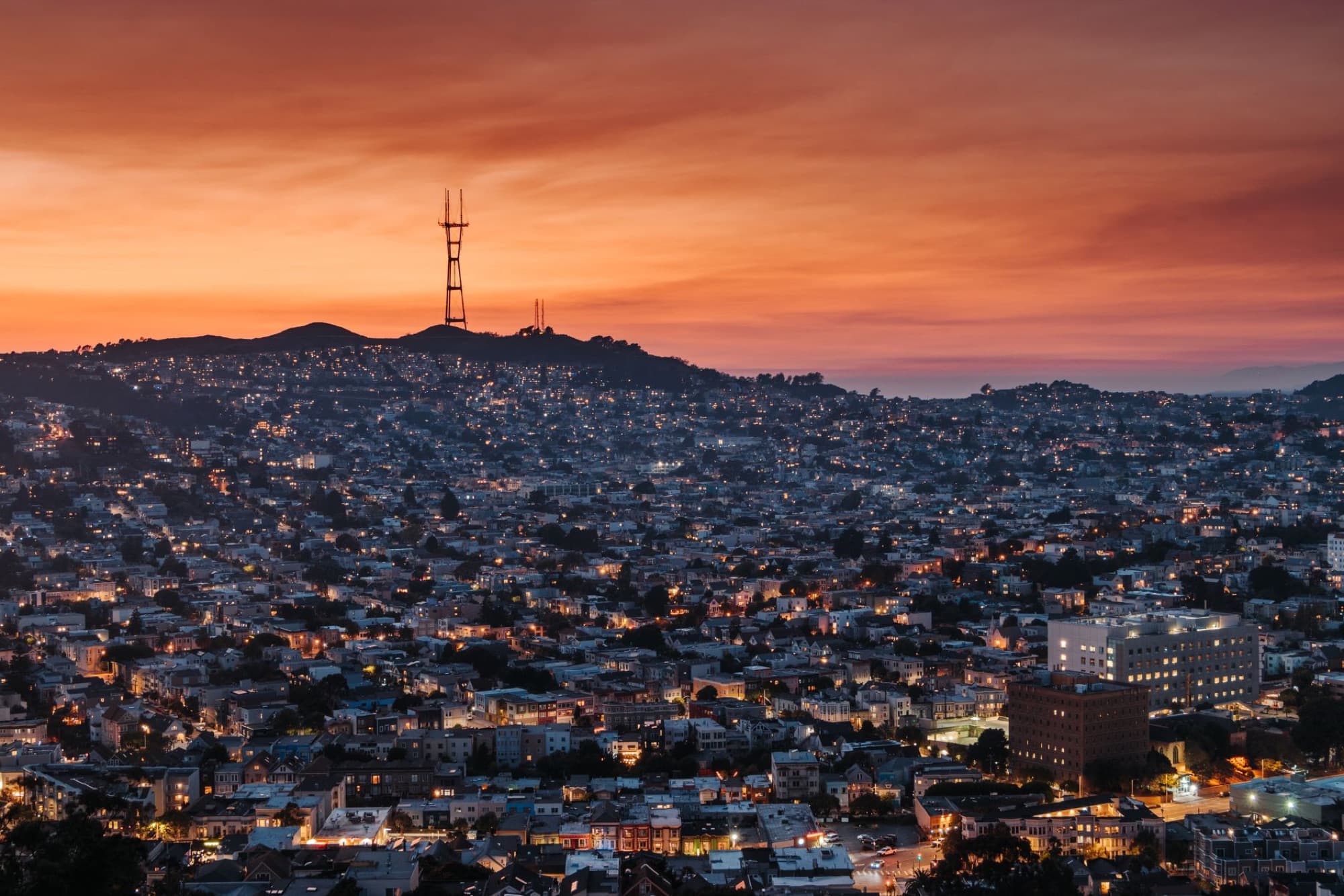 Aerial view of bright night lights of residential city district under colorful sunset sky
