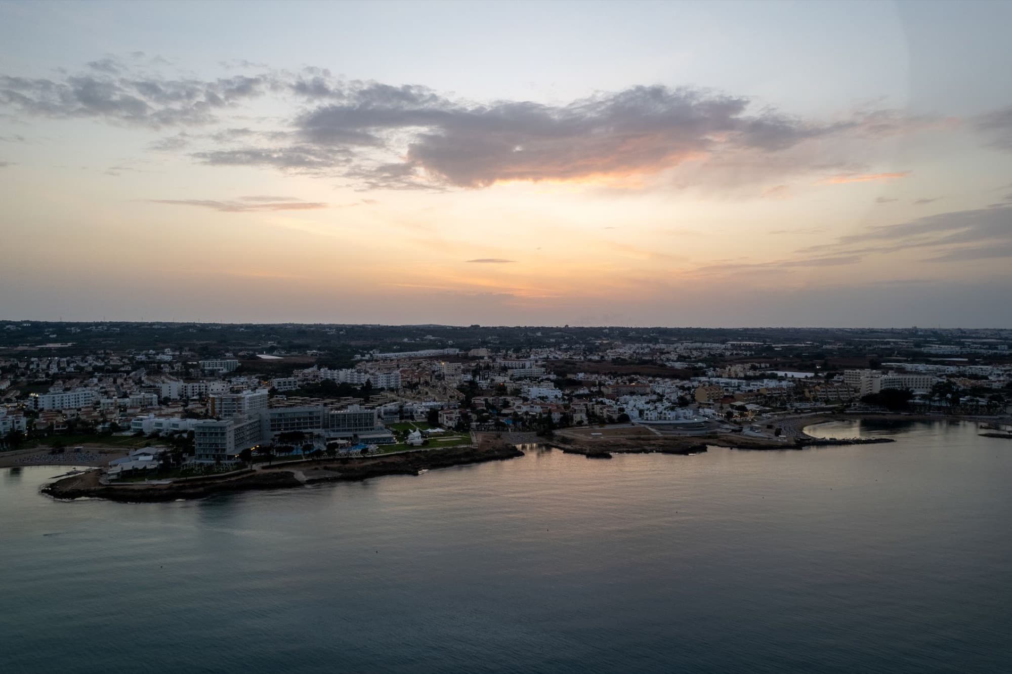 Captivating aerial sunset view of Pernera's coastline with city and sea. Tranquil evening in Cyprus.