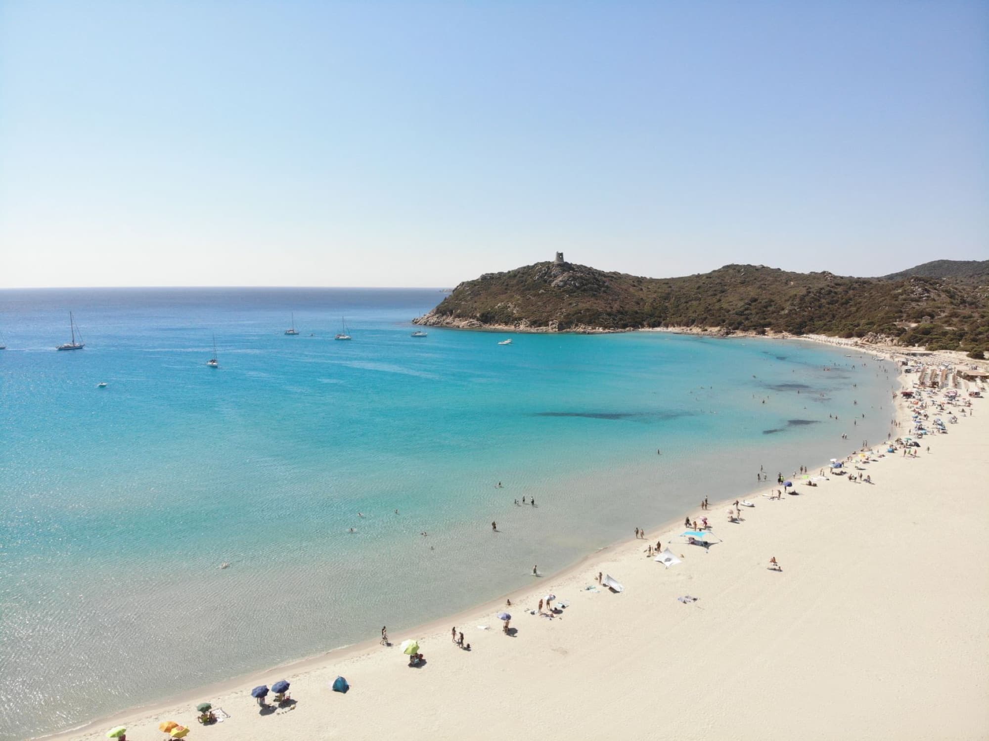 Drone shot capturing the vibrant turquoise waters and pristine beaches of Sardegna, Italy, full of life.