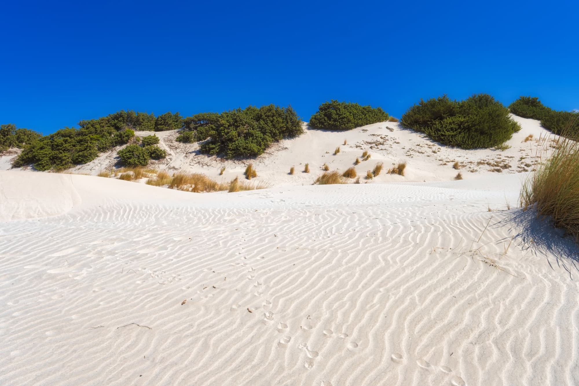 Stunning white sand dunes under clear blue sky in Porto Pino, Sardegna, Italy.