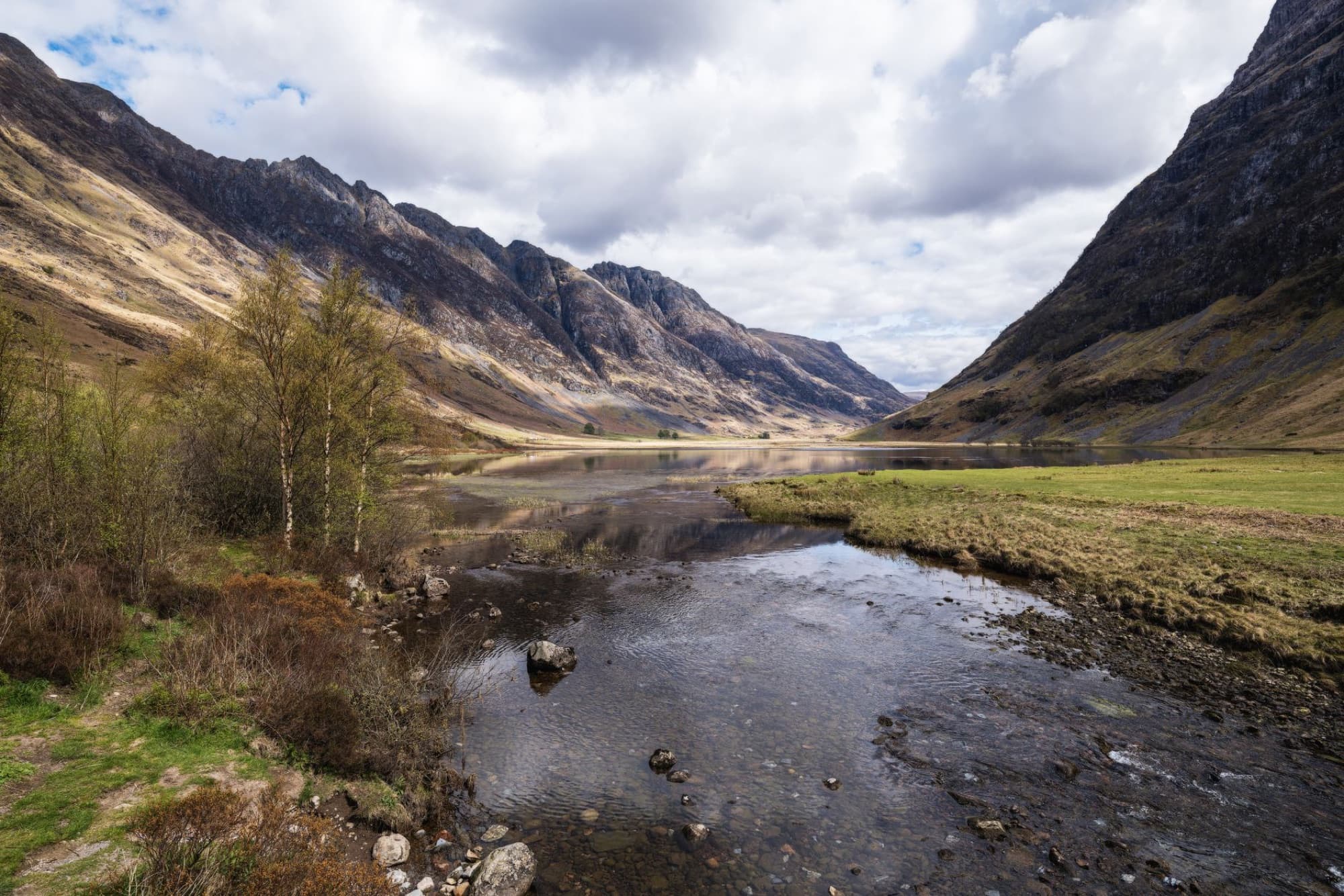 Beautiful view of Glencoe Valley with mountains and calm river in the Scottish Highlands.