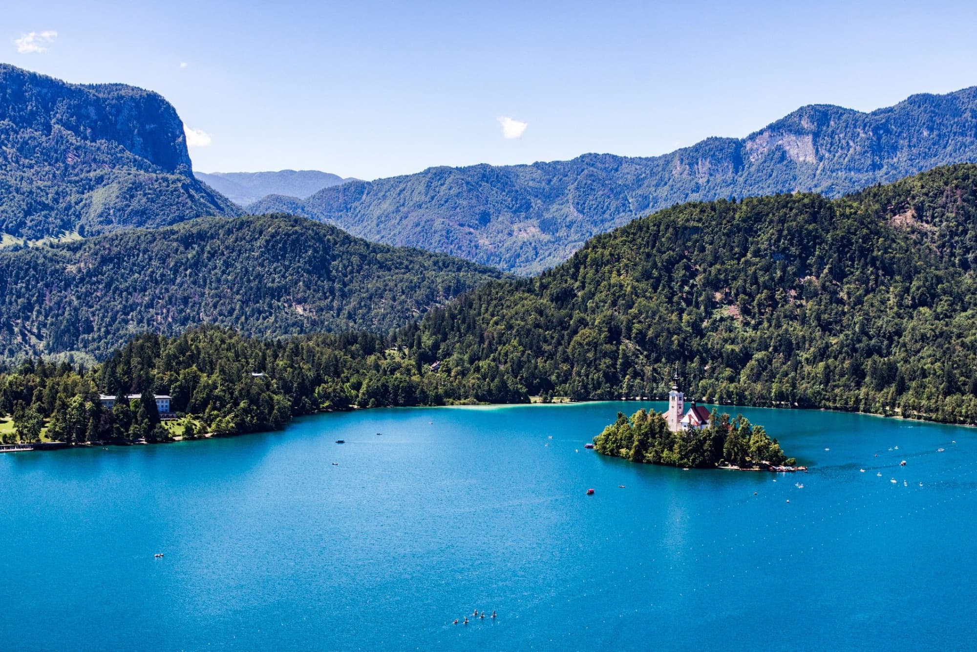 Scenic aerial view of Lake Bled with its iconic island church in Slovenia, surrounded by lush green mountains.