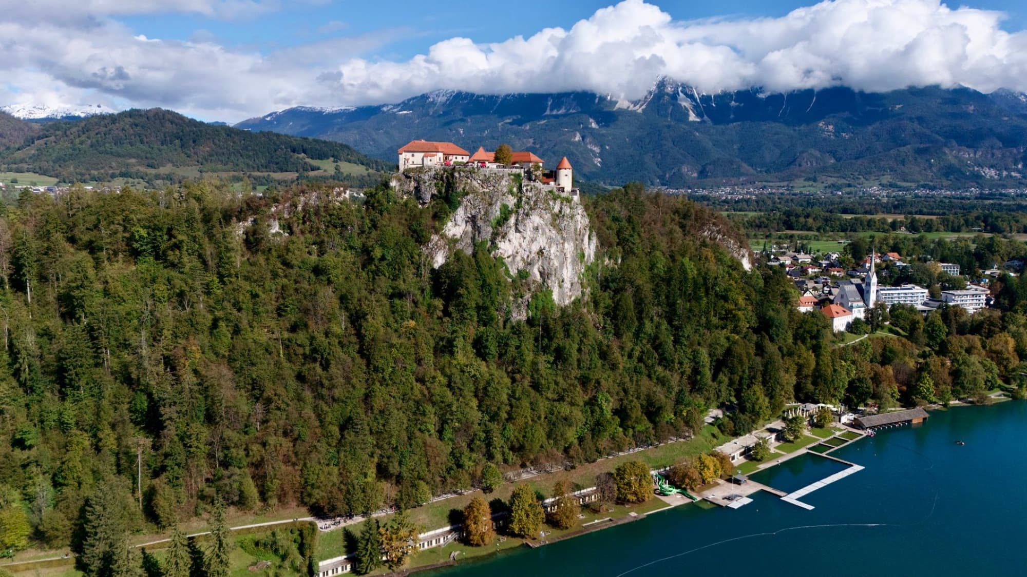 Stunning aerial view of Bled Castle on a lush hill overlooking Lake Bled in Slovenia.