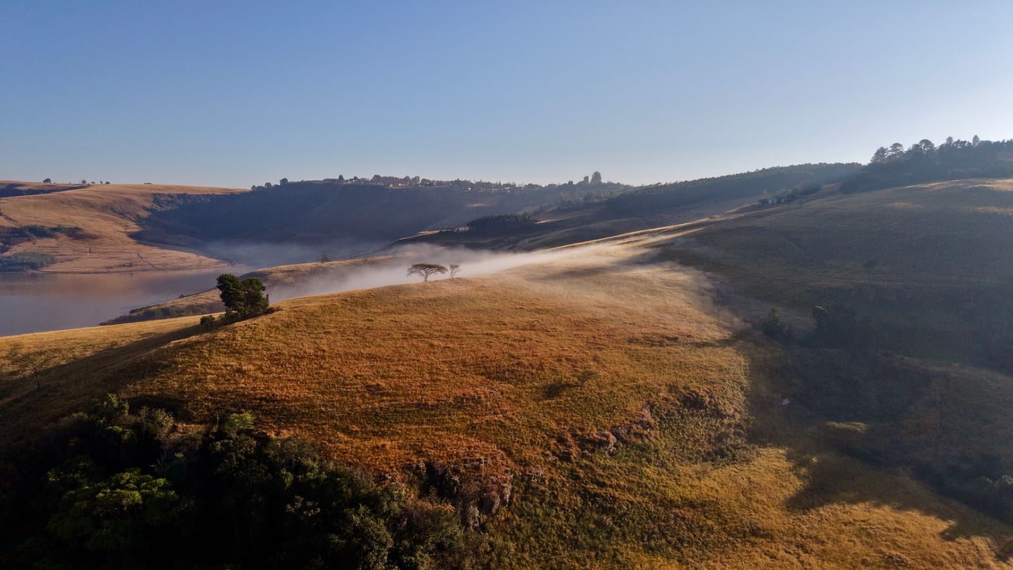 A serene aerial view of mist-covered hills in the Free State, South Africa, at sunrise.