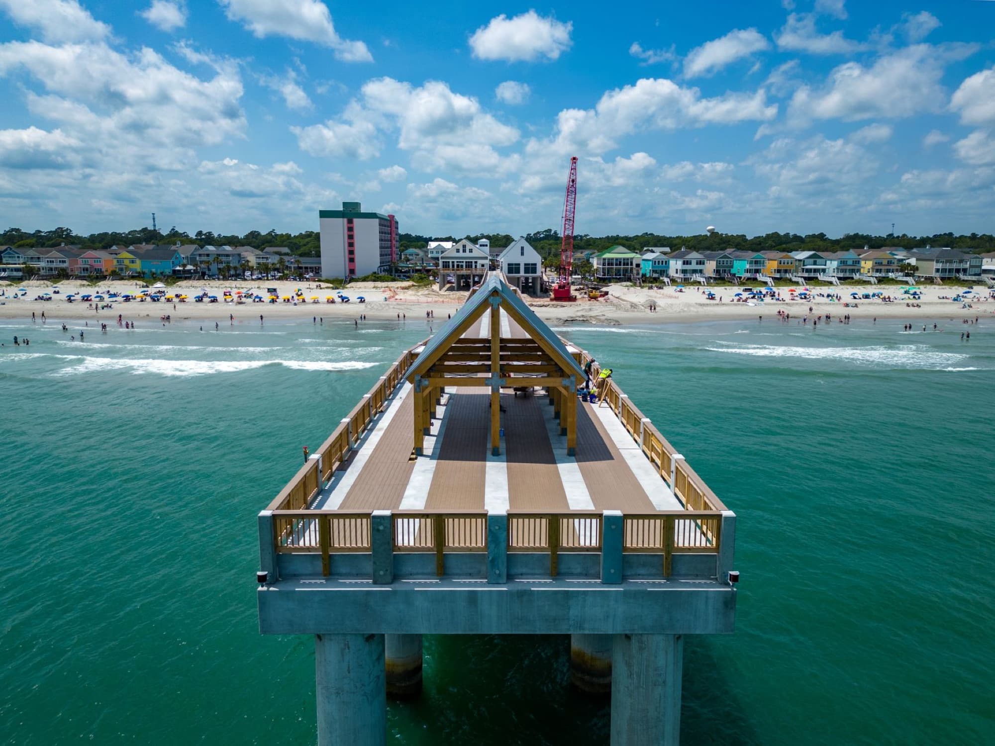 Vibrant aerial view of Surfside Beach Pier in South Carolina with tourists and beachgoers enjoying the summer day.