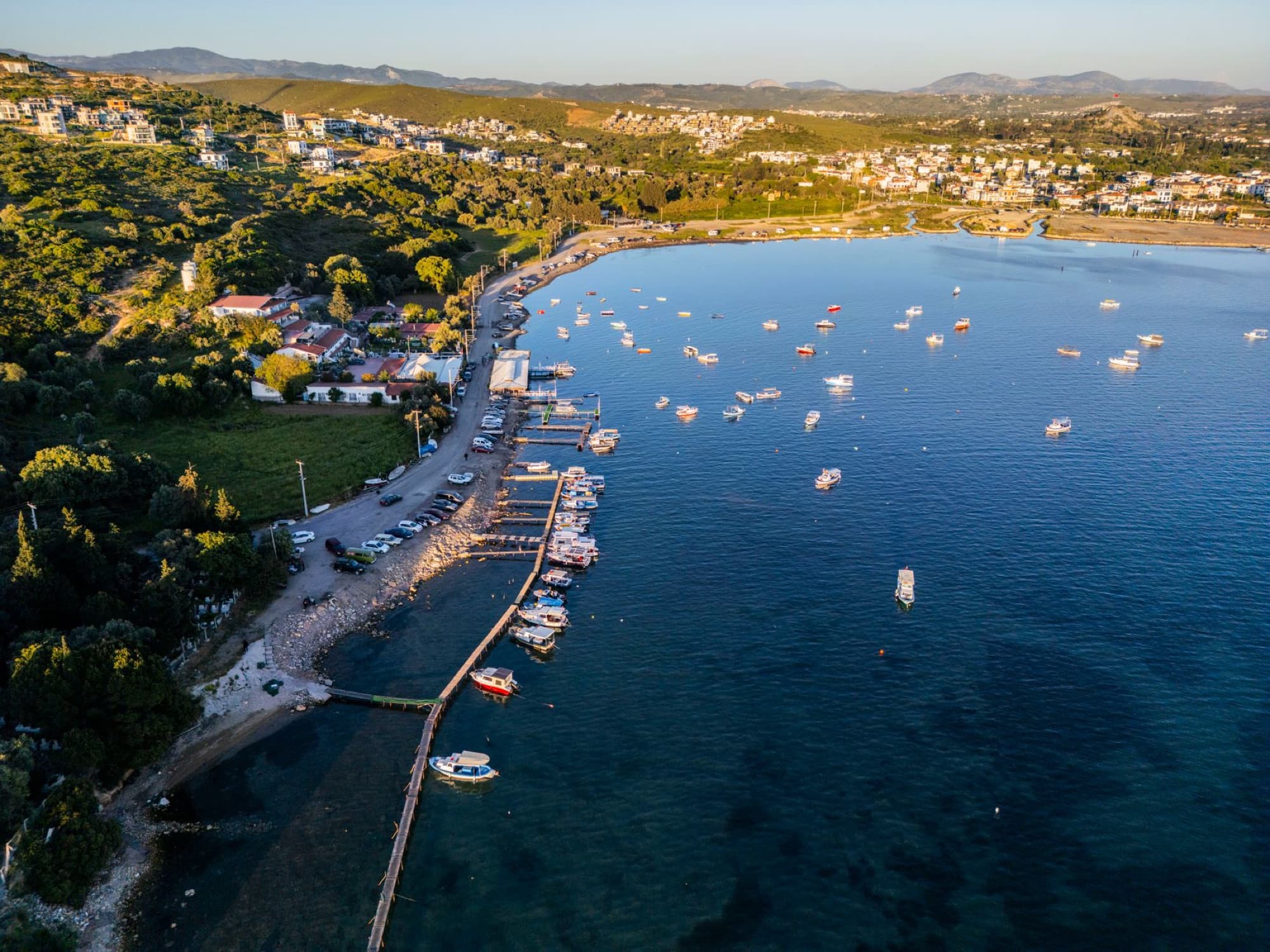 A stunning aerial view of Sığacık harbor in İzmir, Türkiye, showcasing boats and a scenic coastal landscape.