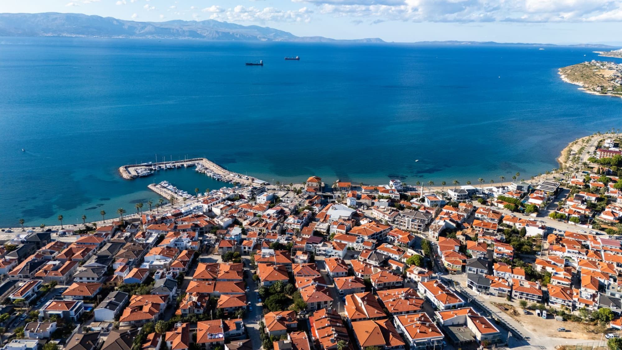 Aerial view of a vibrant coastal town with a marina and deep blue sea in Turkey.
