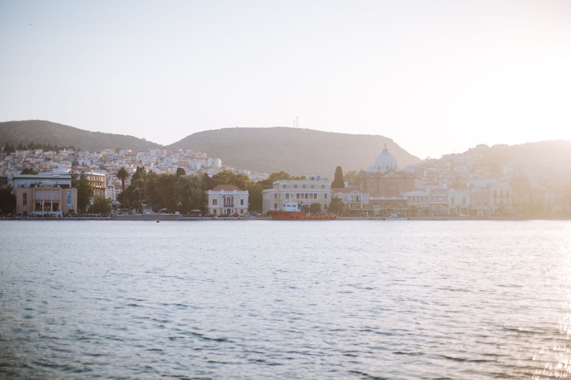 Beautiful coastal city scene with mountains and sea, capturing a soft sunset glow.