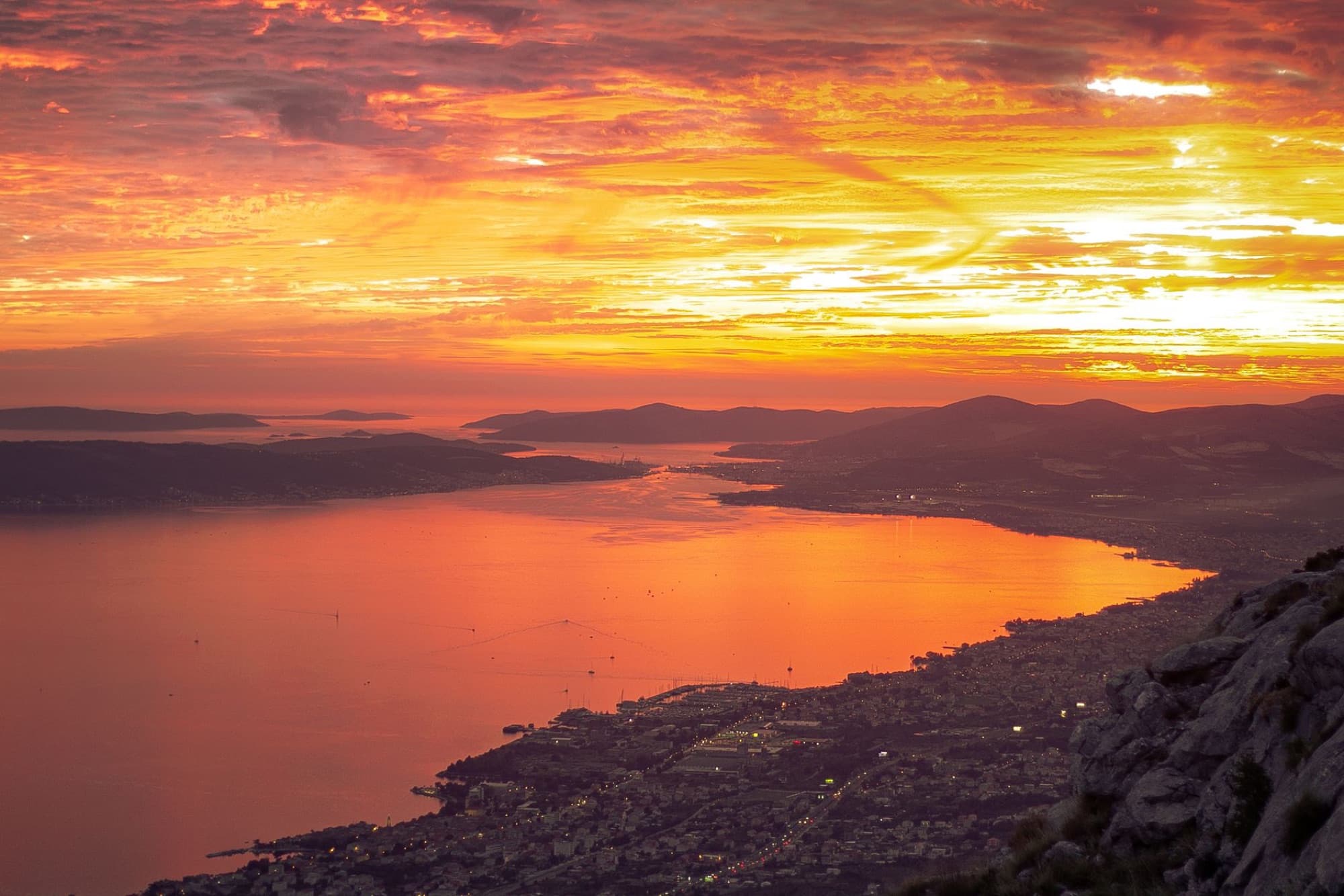 A breathtaking aerial view of Split, Croatia at sunset, highlighting vibrant colors over the sea and mountains.