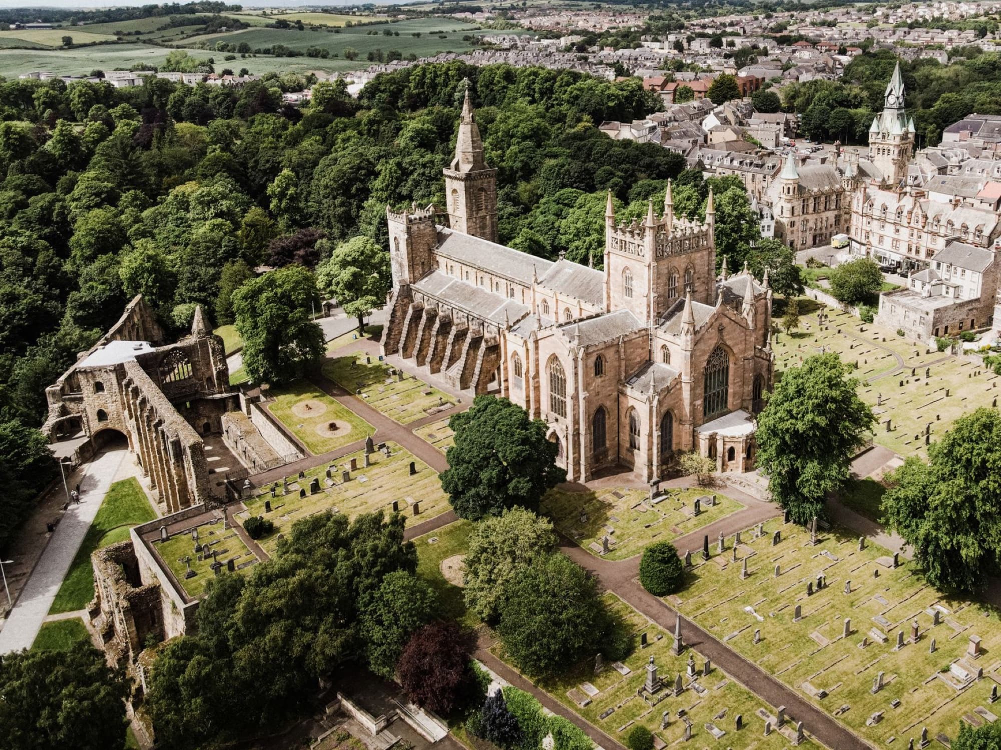 Aerial shot of a historic cathedral surrounded by trees and a cemetery.