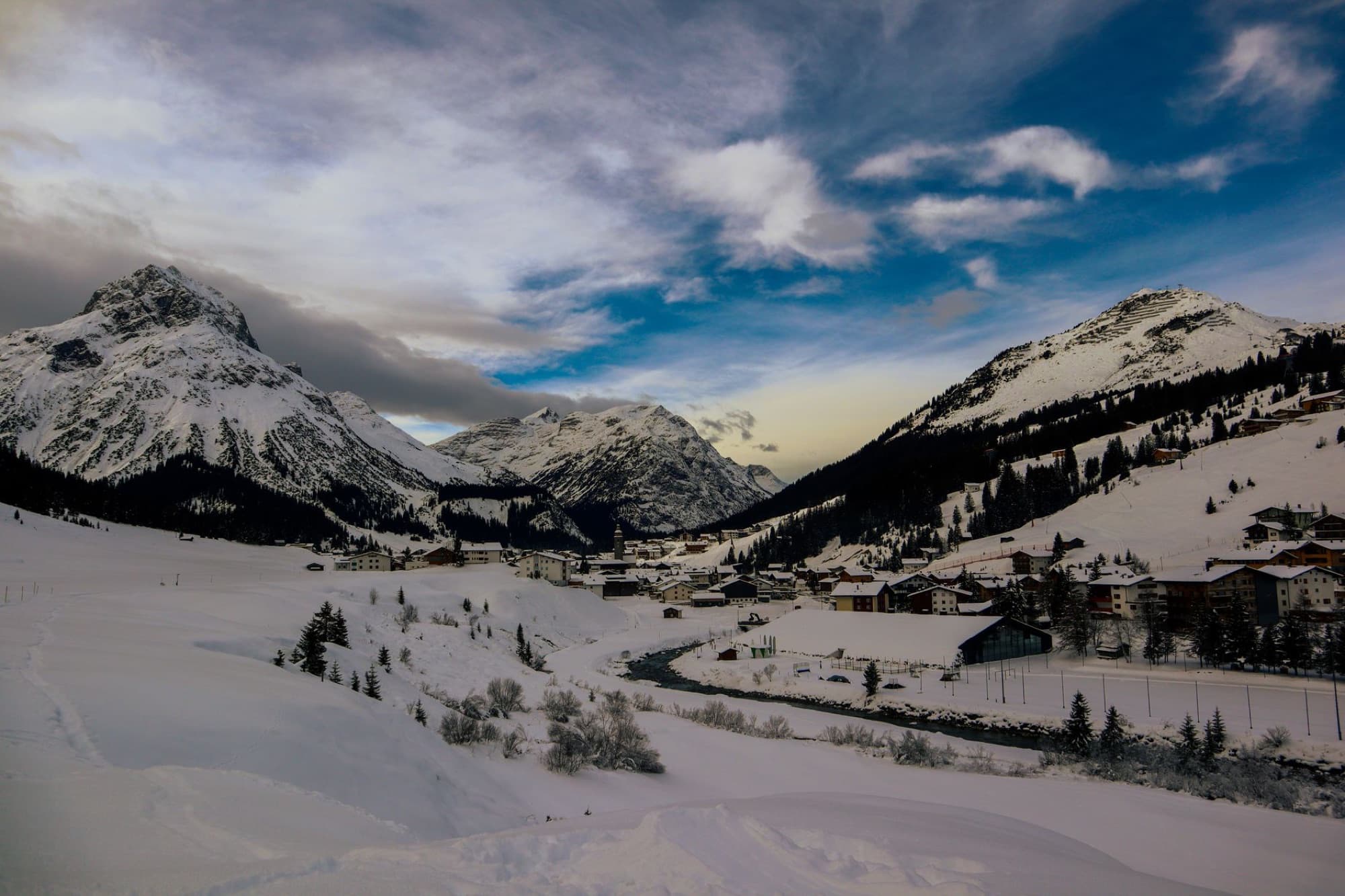 Scenic winter landscape of Lech, Austria with snow-covered mountains and a serene village.