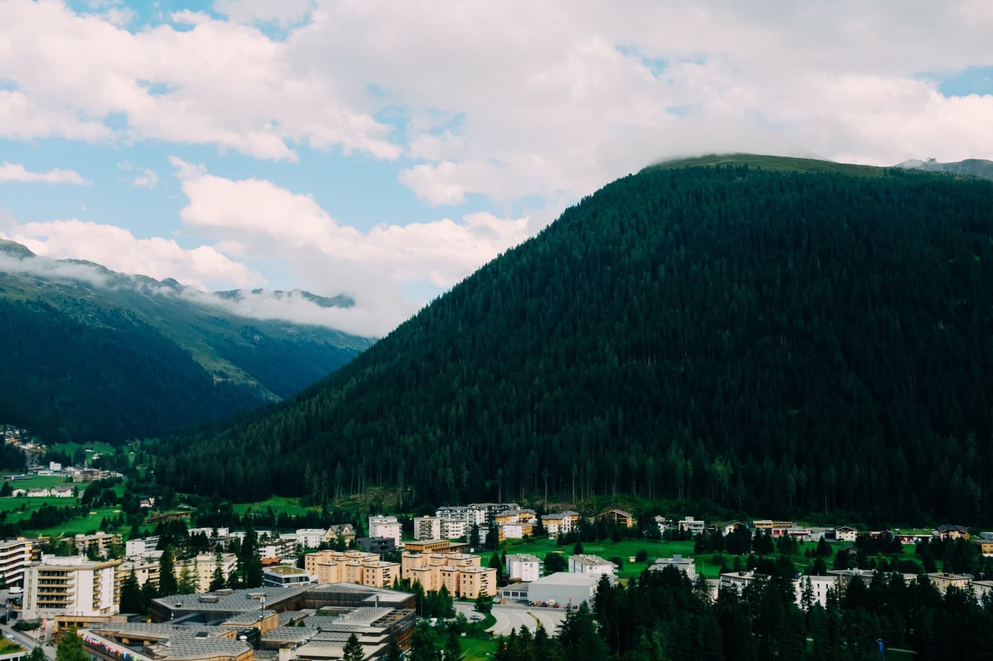 A breathtaking aerial view of a serene alpine town nestled at the foot of lush mountains.