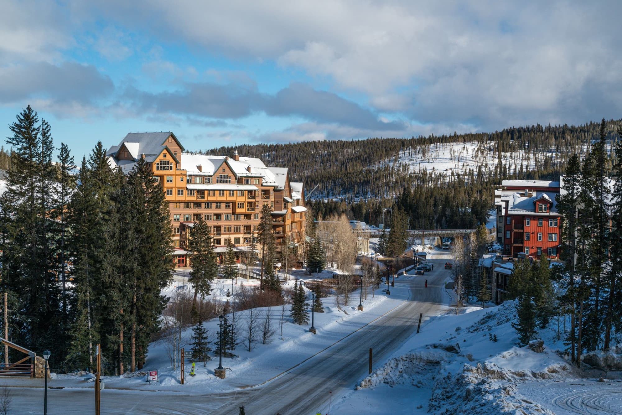 Aerial view of a snowy mountain resort town with architecture and trees in winter.
