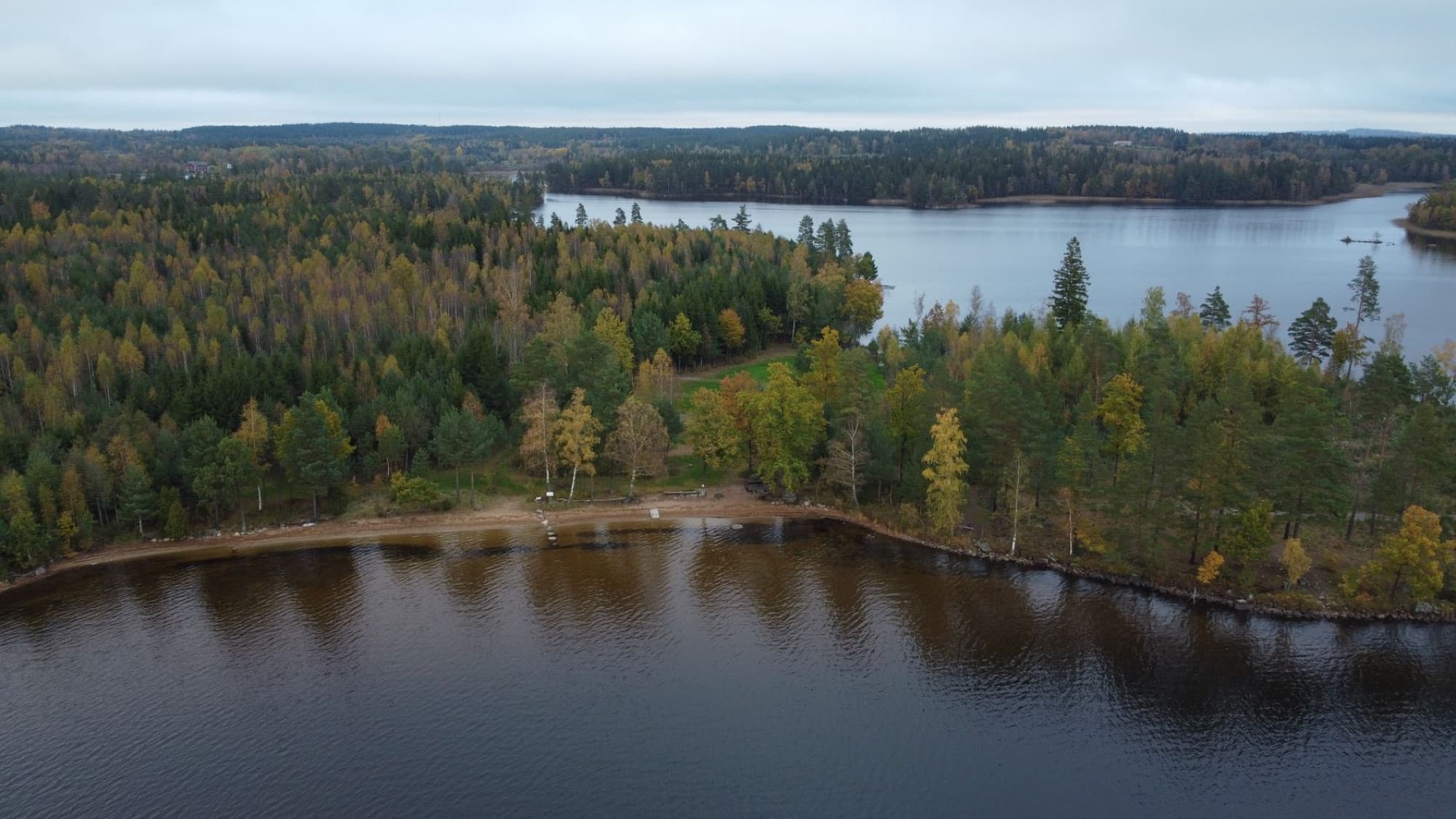 Aerial view capturing the serene lake and lush forests in Kronoberg County, Sweden.