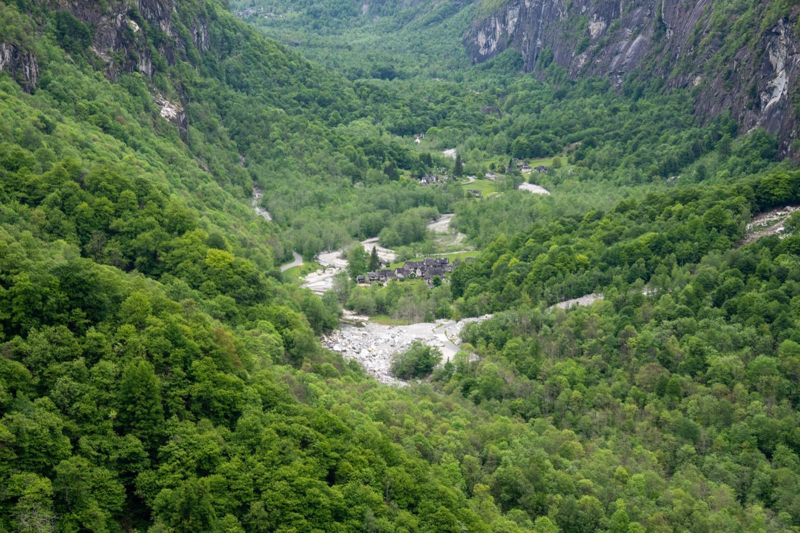 Stunning aerial shot of a verdant valley in Cevio, Ticino with dense forests and a flowing river.