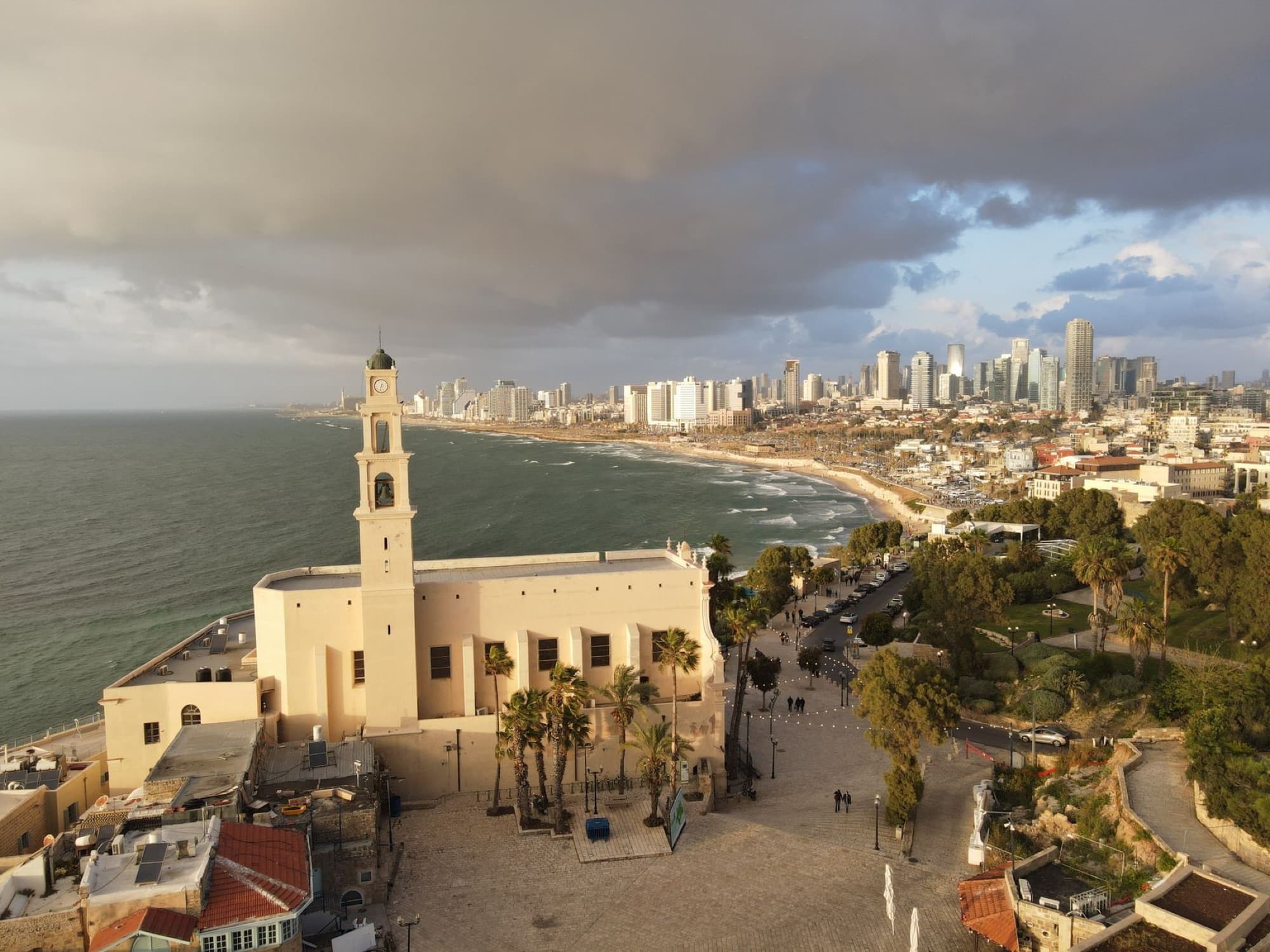 A picturesque aerial view of a church tower and Tel Aviv coastline on a sunny day.