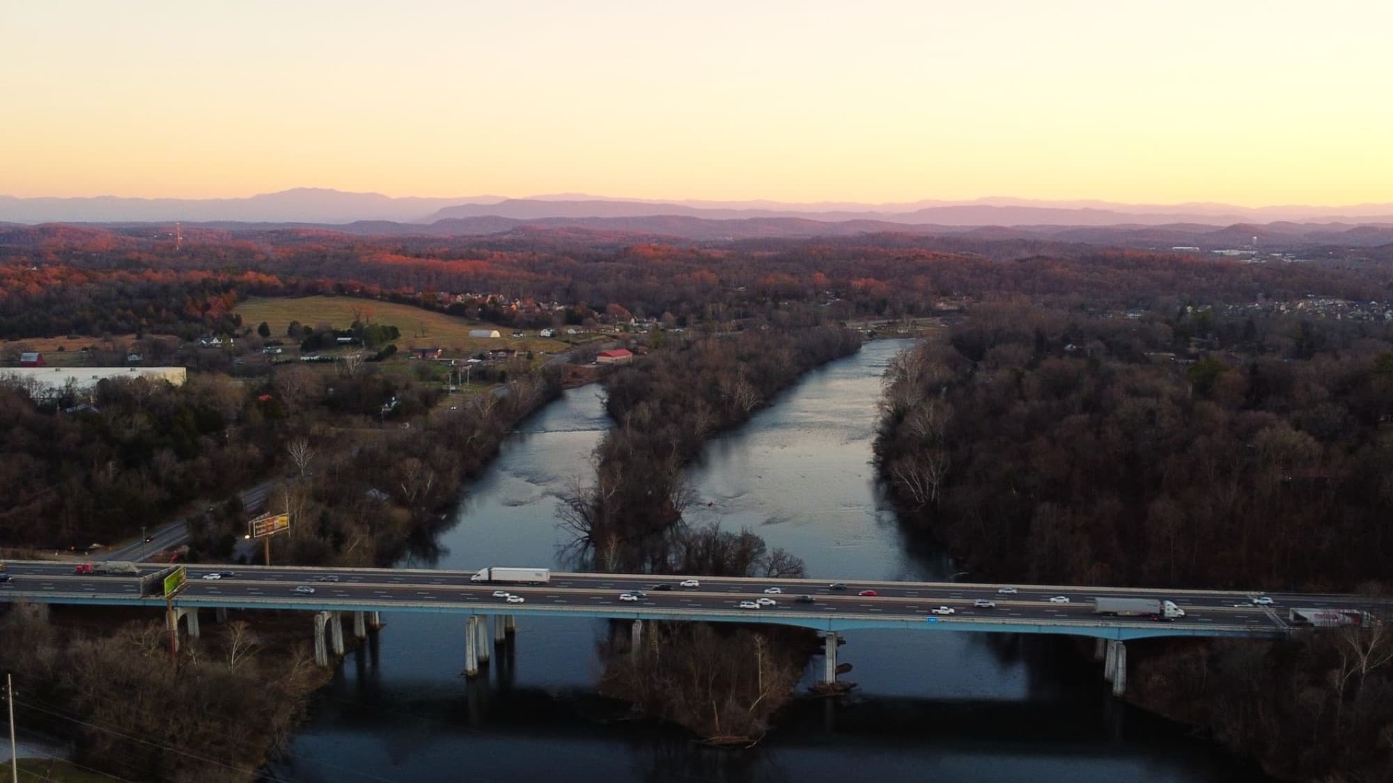 Aerial view of a bridge over Holston River in Tennessee with the Smoky Mountains in the background at sunset.