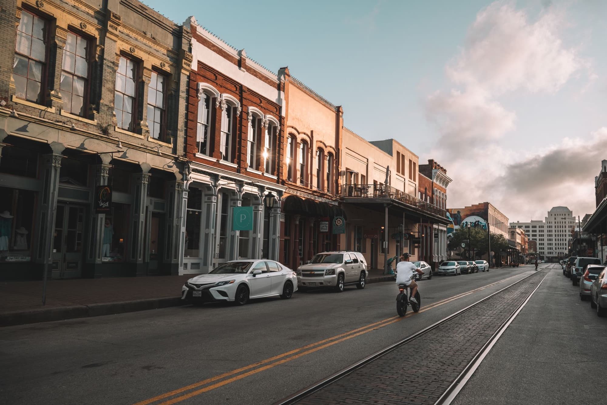 Scenic view of a historic downtown street in Galveston, Texas, with classic architecture and vehicles.