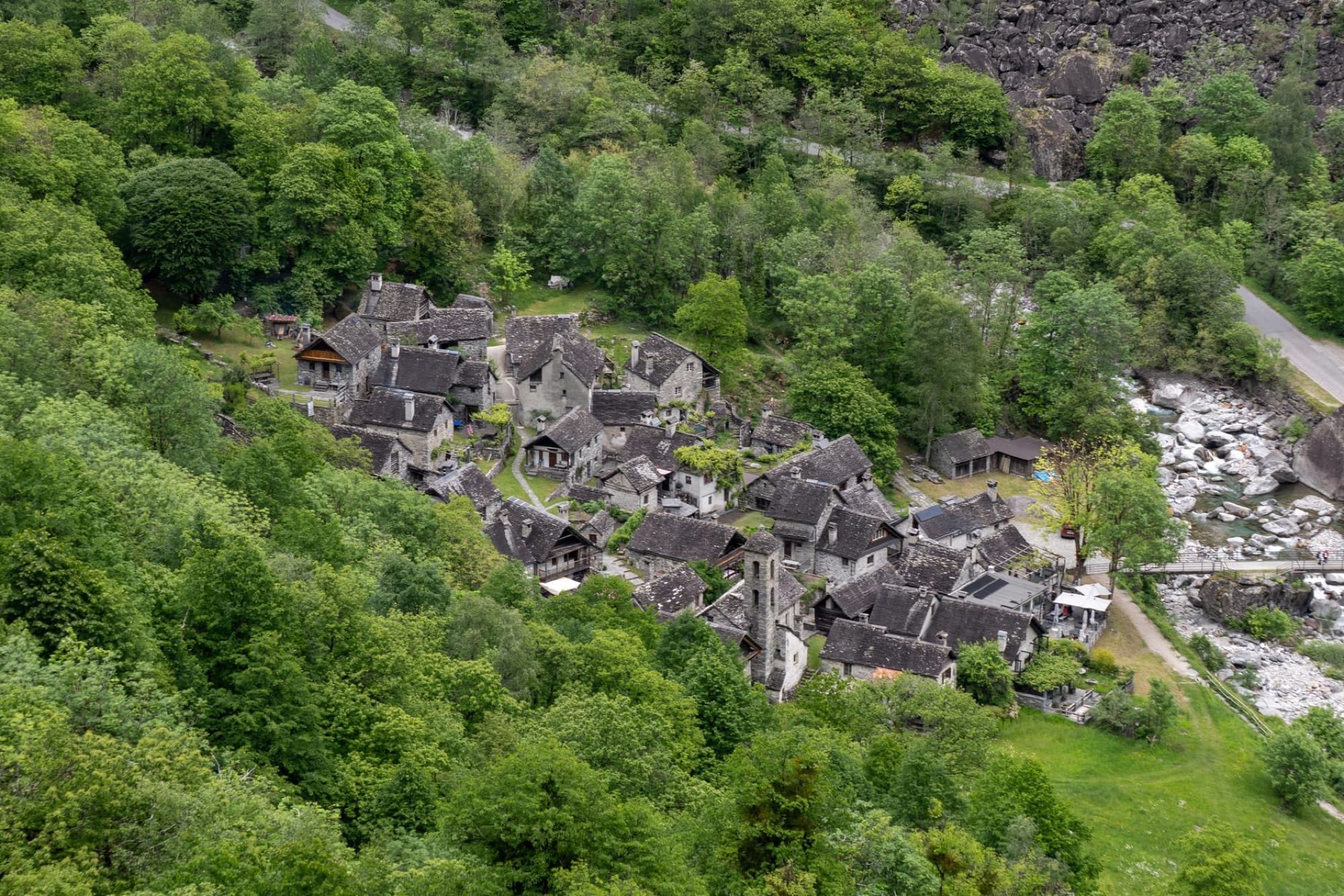 Aerial shot of a historic village surrounded by dense forests in Cevio, Ticino, Switzerland, showcasing rustic charm and scenic beauty.