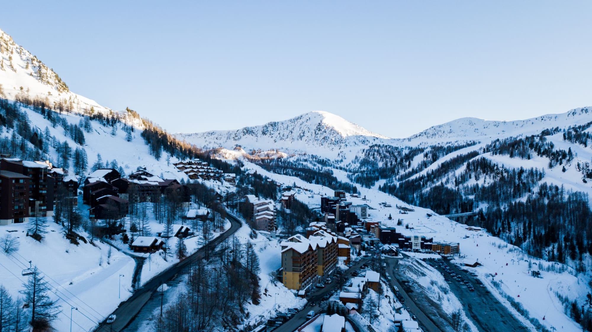 Stunning aerial shot of a snow-covered alpine village with mountains in the background during sunrise.