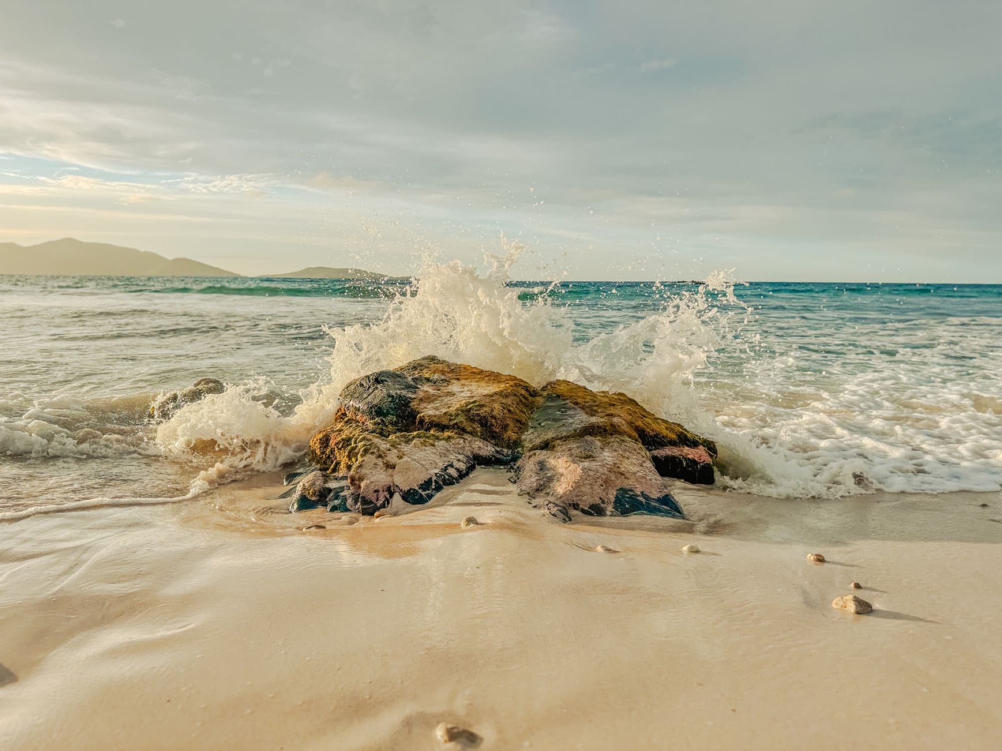 A peaceful beach scene with waves crashing on rocks at Tortola, British Virgin Islands.