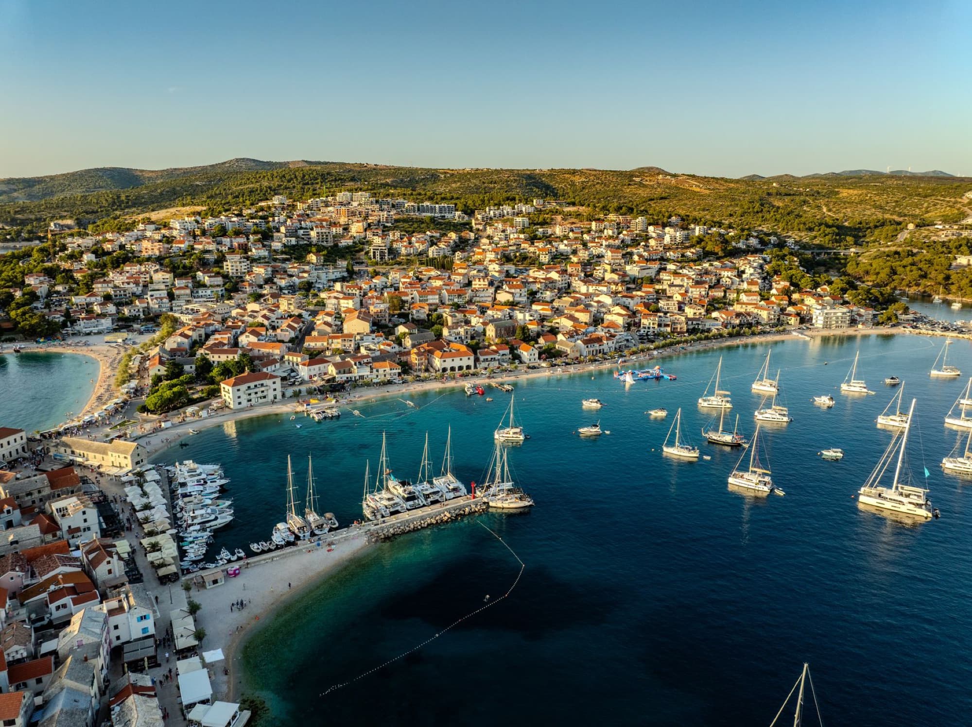Stunning aerial view of Primošten's vibrant harbor and town, Croatia, at sunset.