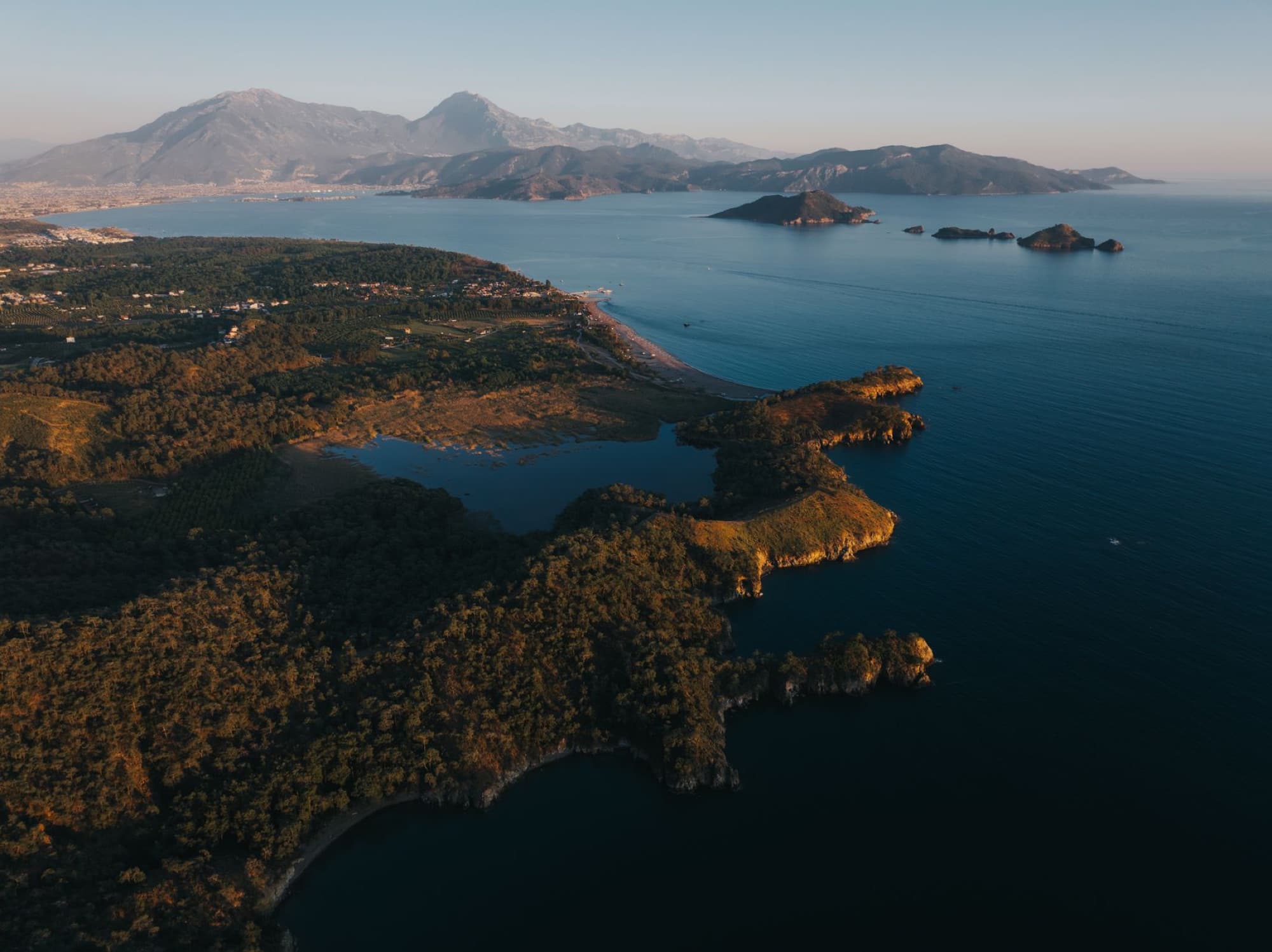 Sweeping aerial view of the Turkish coastline with mountains and islands at sunset, showcasing natural beauty.