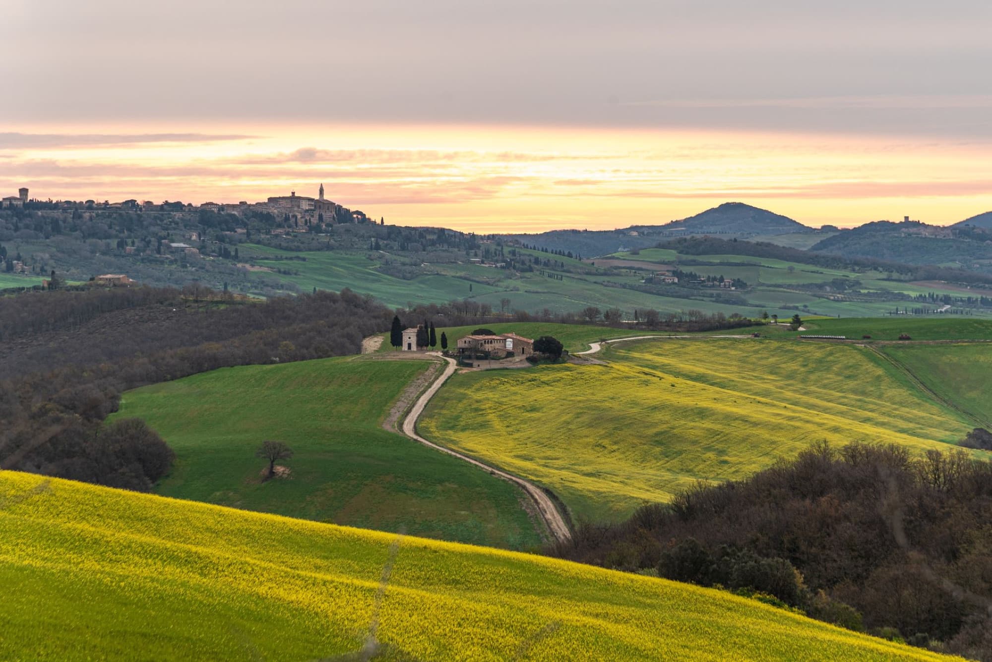 Beautiful landscape of rolling hills and distant town in Tuscany, Italy during sunset.
