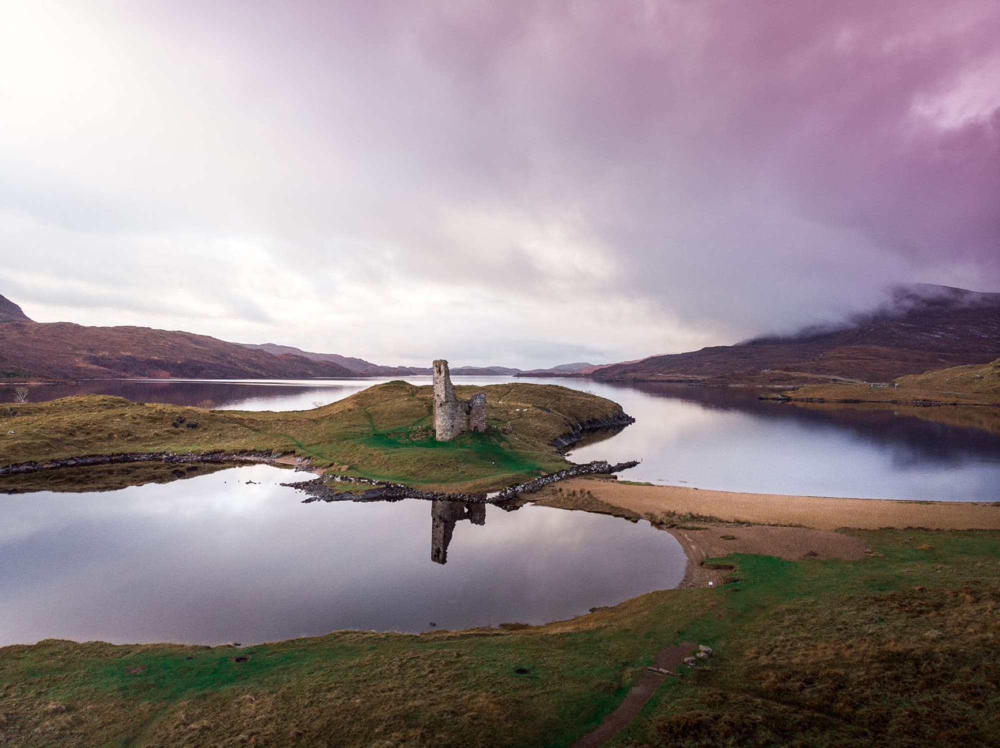 Aerial view of Ardvreck Castle reflecting on a tranquil lake in Lairg, Scotland.