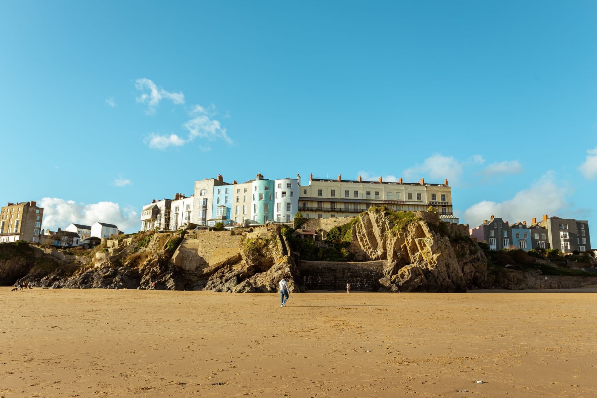 Picturesque view of coastal cliffs and buildings in Tenby, Wales under a clear blue sky.
