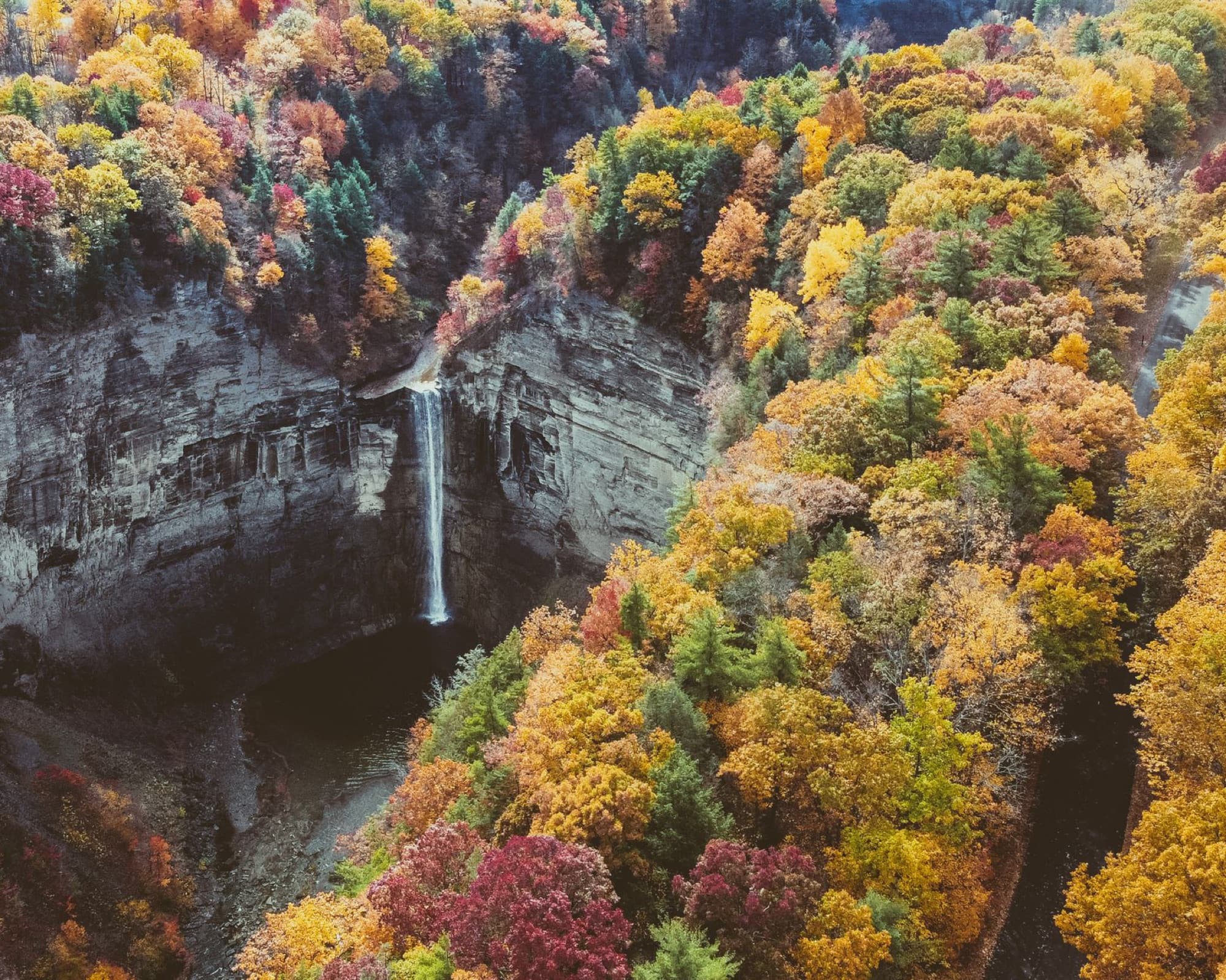 A breathtaking aerial view of Taughannock Falls amid colorful autumn foliage in Upstate New York.