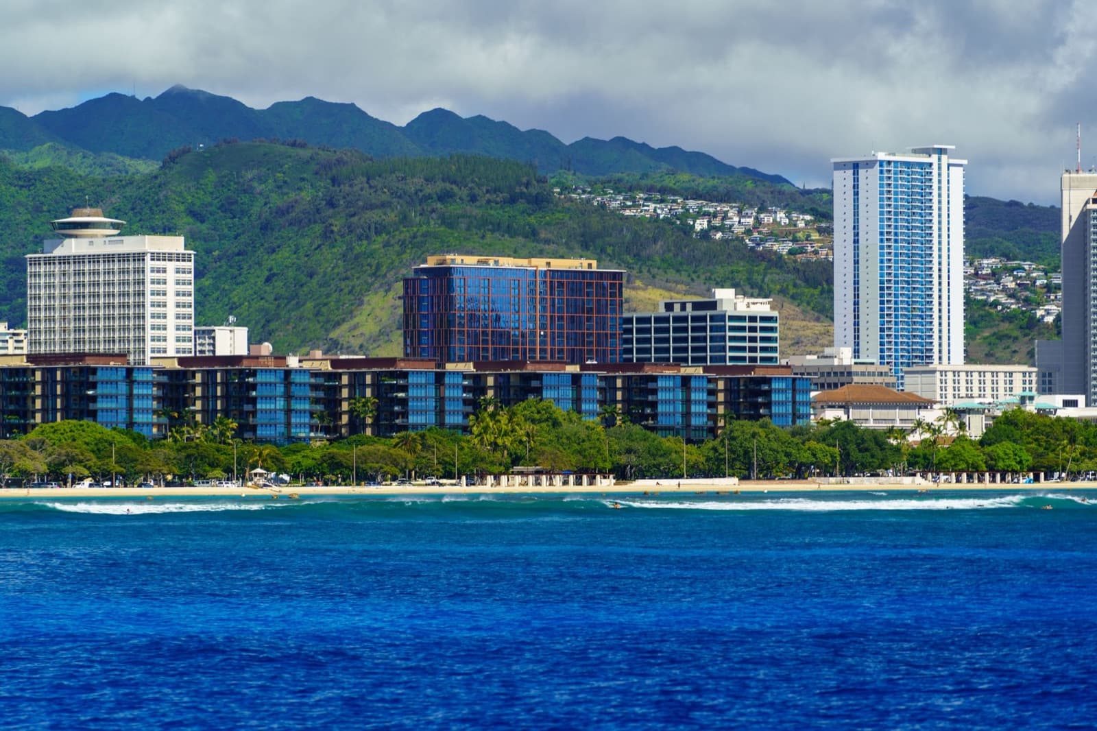 Scenic view of Honolulu skyline and ocean against the backdrop of lush green mountains, Hawaii.