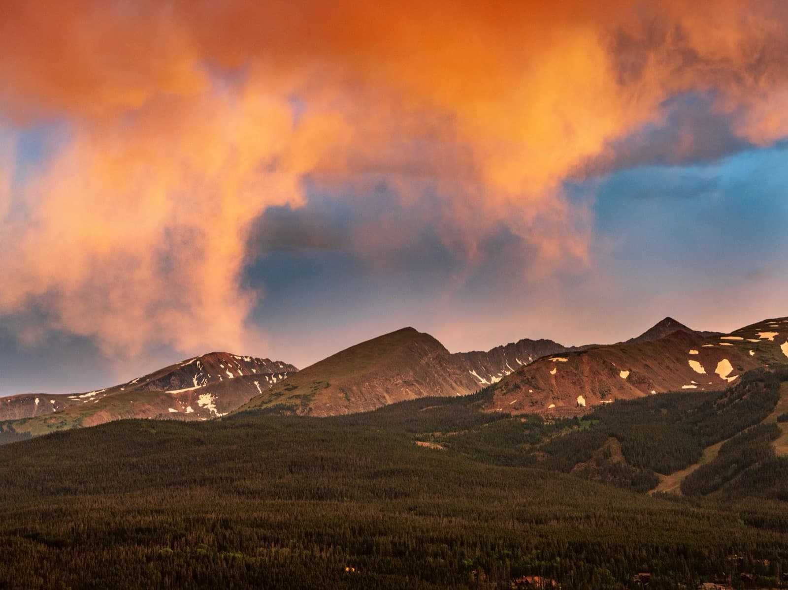 Stunning sunset over the mountains in Breckenridge, Colorado, showcasing vibrant clouds and scenic landscape.