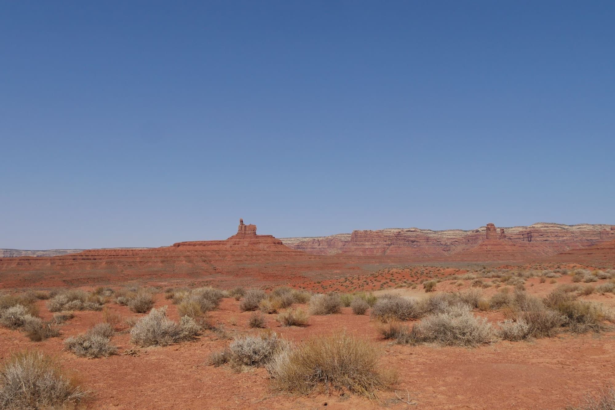 Beautiful desert landscape featuring red rock formations under clear blue sky in Utah's Valley of the Gods.