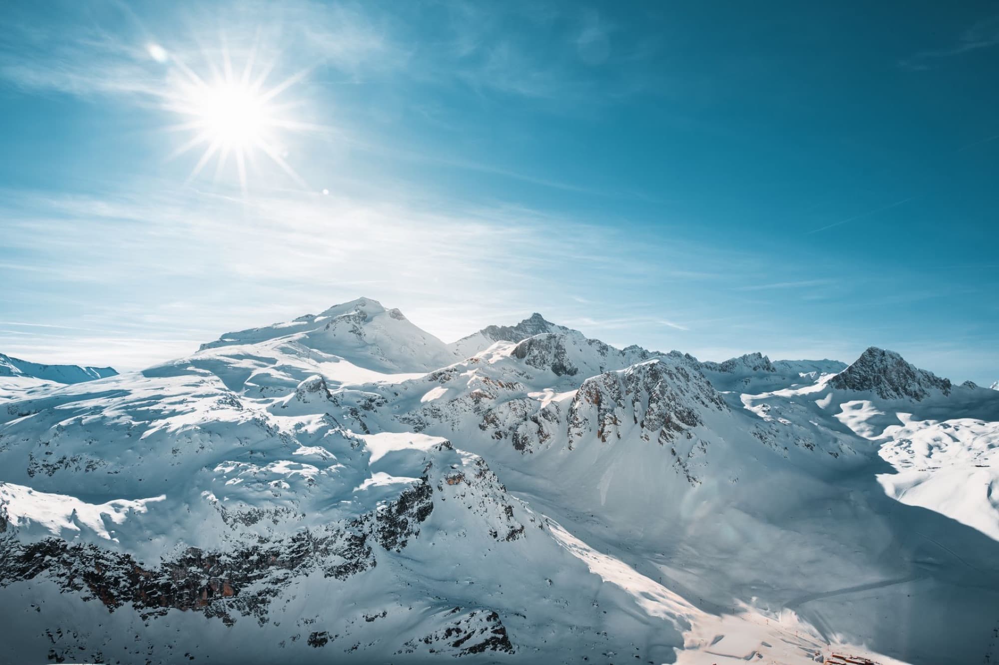 Breathtaking view of snow-covered peaks in Val-d'Isère, France under bright winter sun.