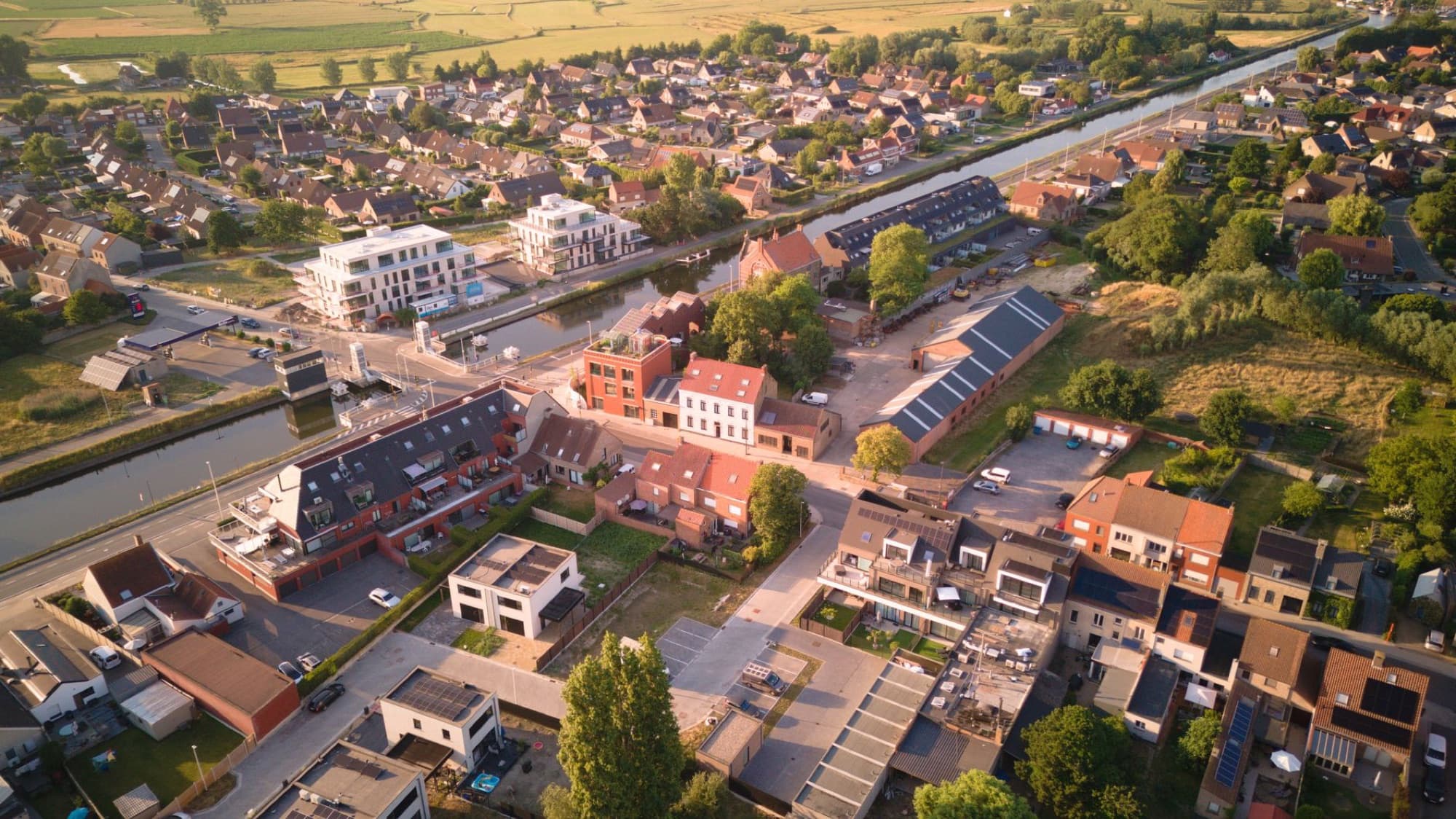 Scenic aerial view of Oudenburg, Belgium, with rooftops and a canal during sunset.