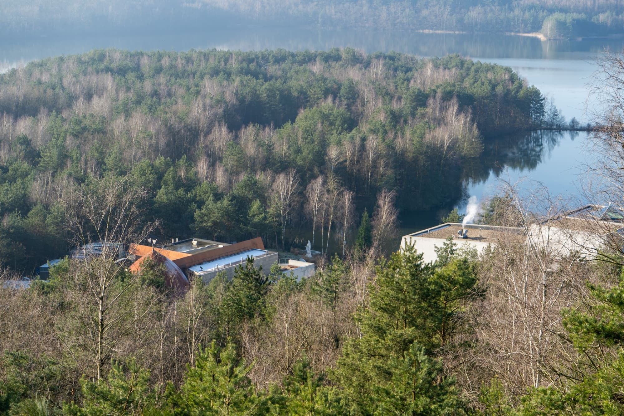 Aerial view of a forested island with buildings in Maasmechelen, Belgium.