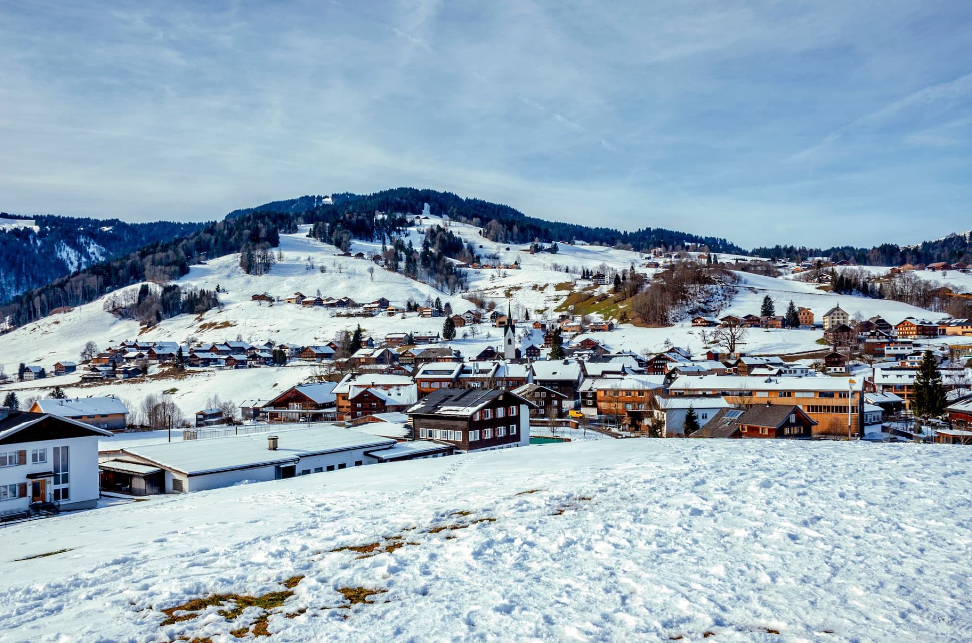 A stunning winter landscape of Schwarzenberg with snow-covered houses and mountains in Vorarlberg, Austria.