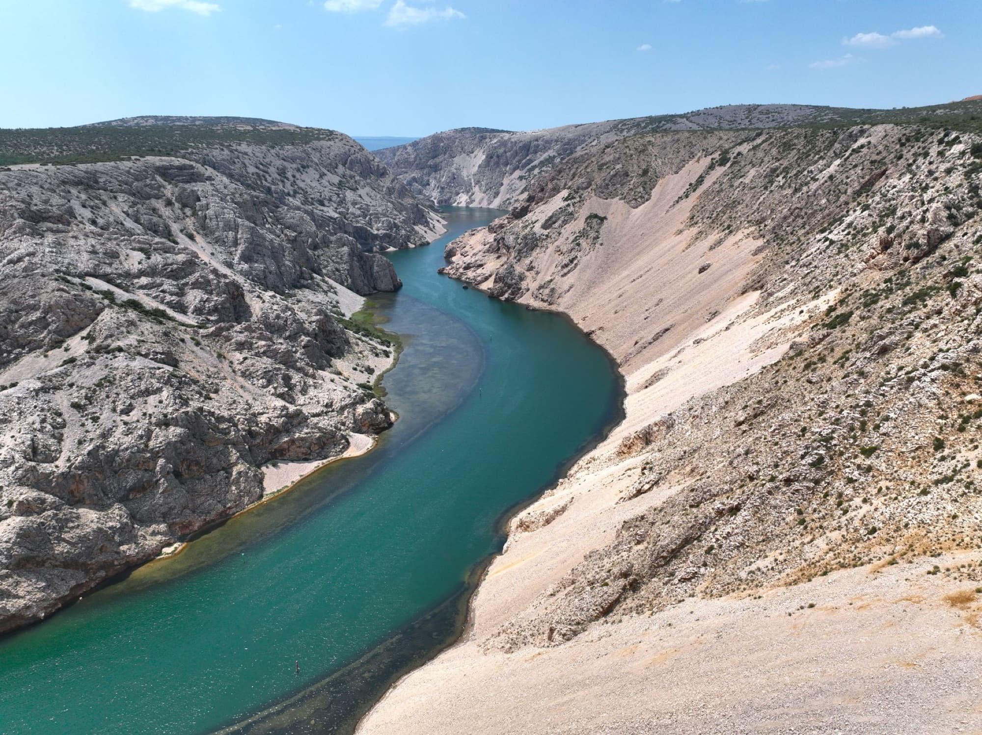 Stunning aerial view of the Zrmanja River winding through a rocky canyon under a clear blue sky.