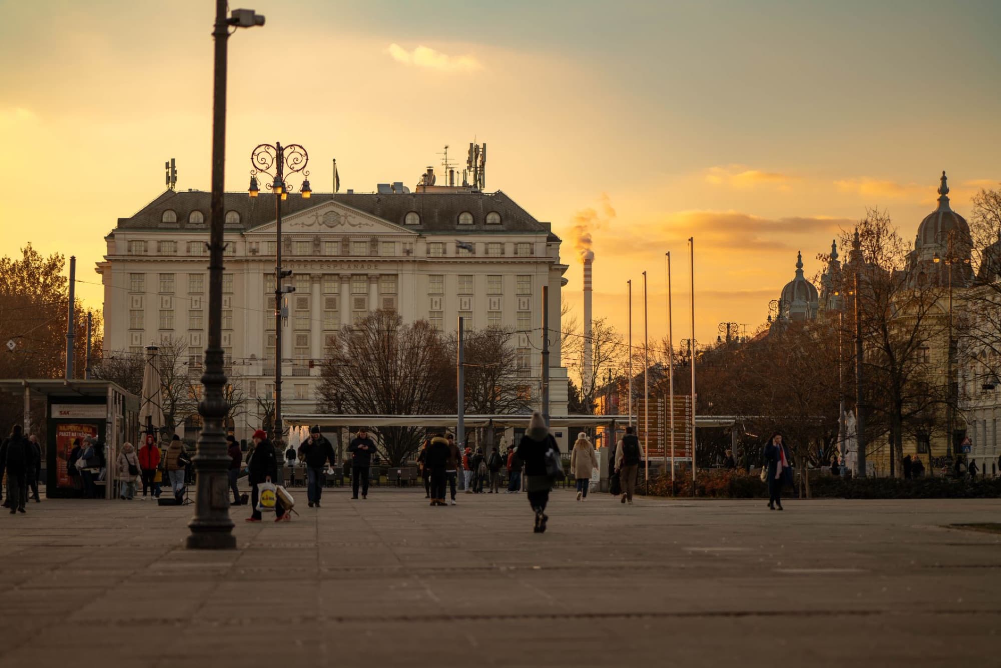 Capture of Zagreb's skyline at sunset, featuring a prominent historic building and city life.