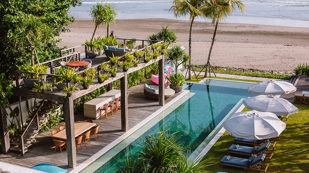Beachfront villa pool deck with parasols and loungers
